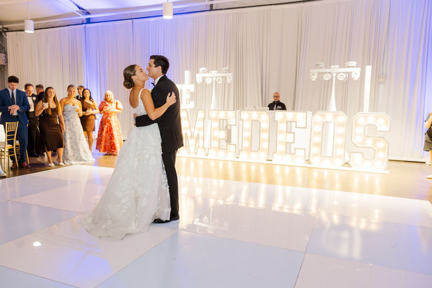 Modern white wedding reception venue with blue uplighting and illuminated candle displays.