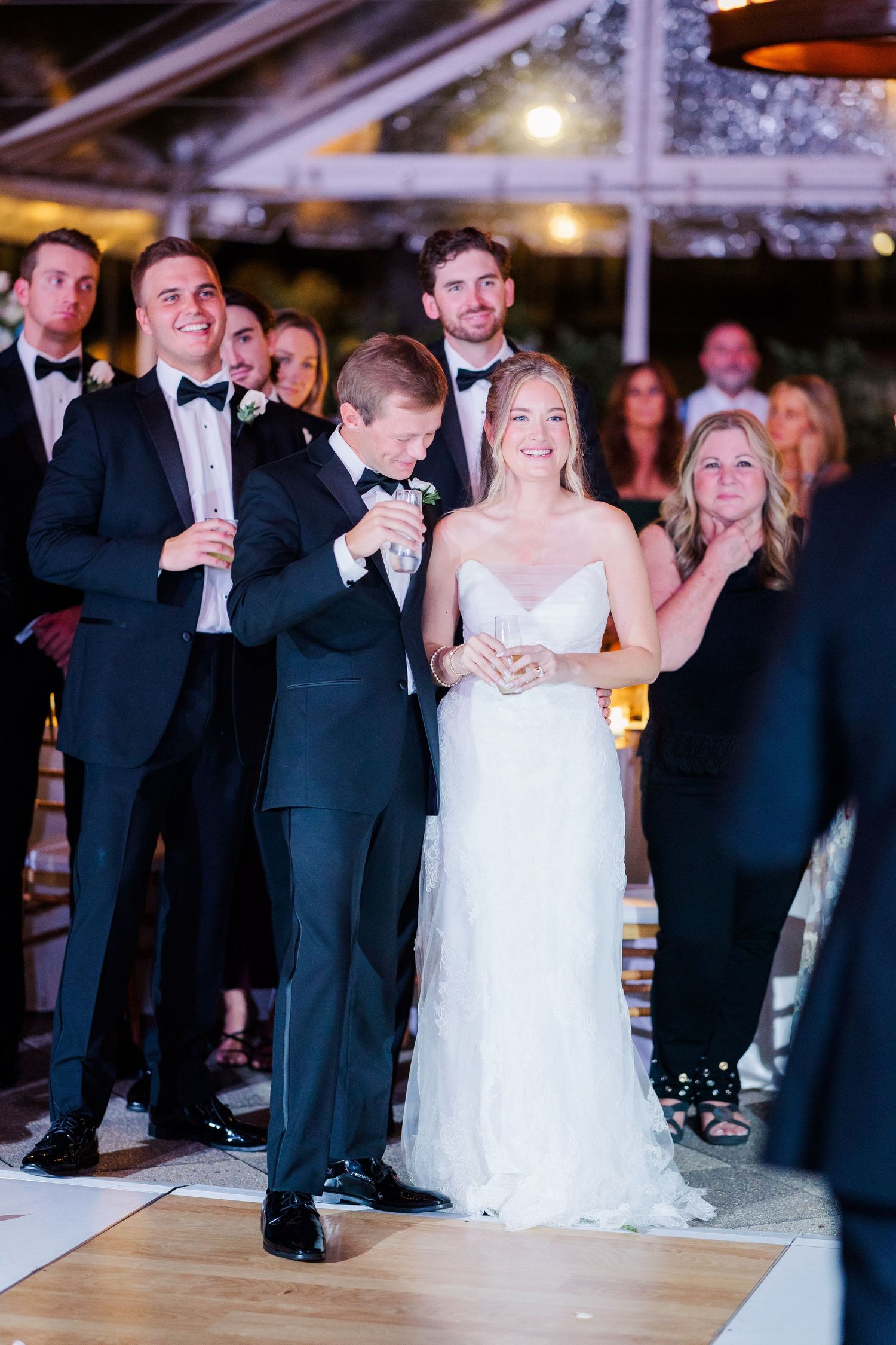 Wedding reception guests gather under tent for evening celebration and dancing.