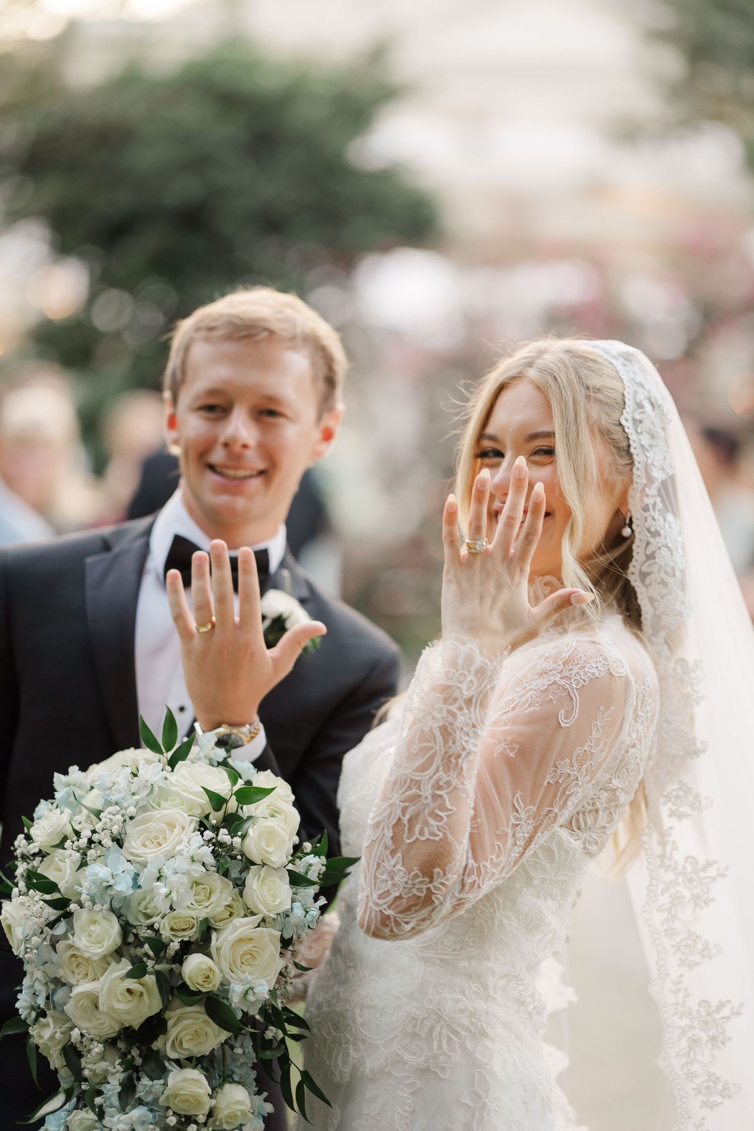 Wedding portraits with white floral bouquet and delicate lace veil against soft outdoor background.