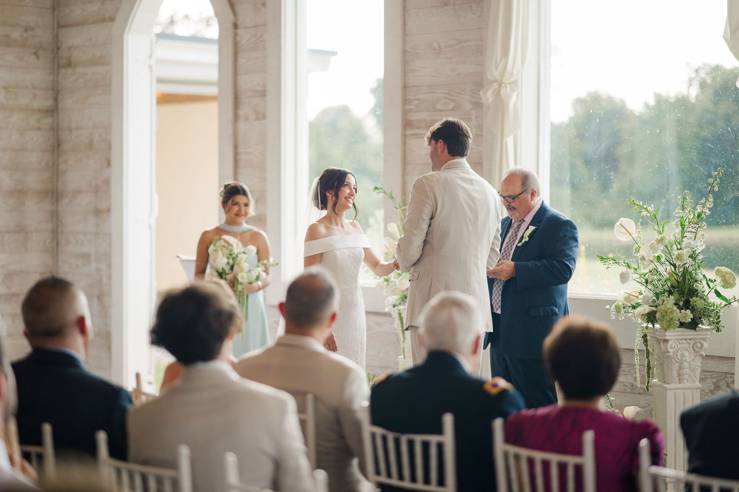 Intimate indoor wedding ceremony with bride and groom exchanging vows before small seated gathering.