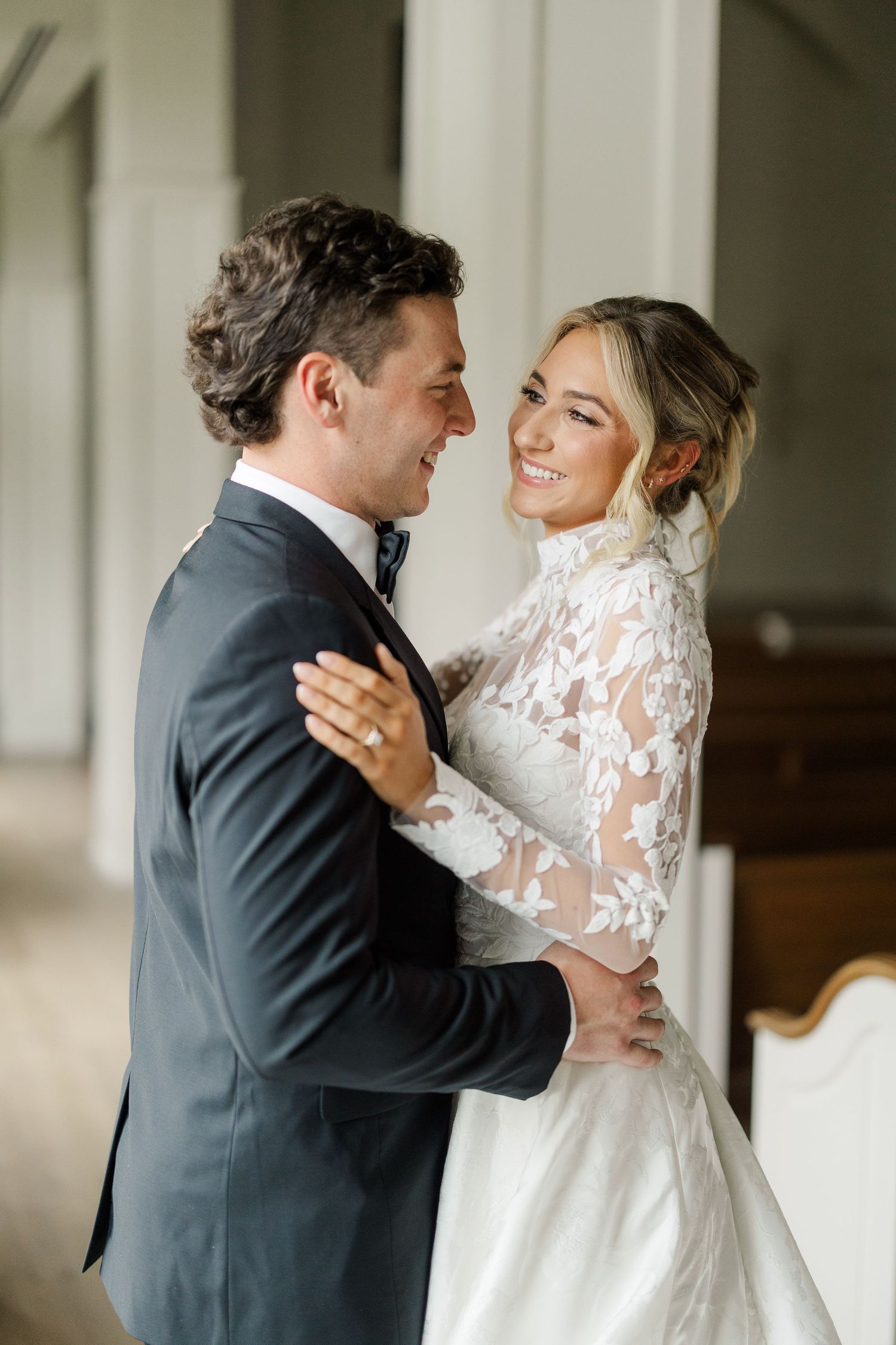 A romantic first look moment between newlyweds in an elegant church hallway.