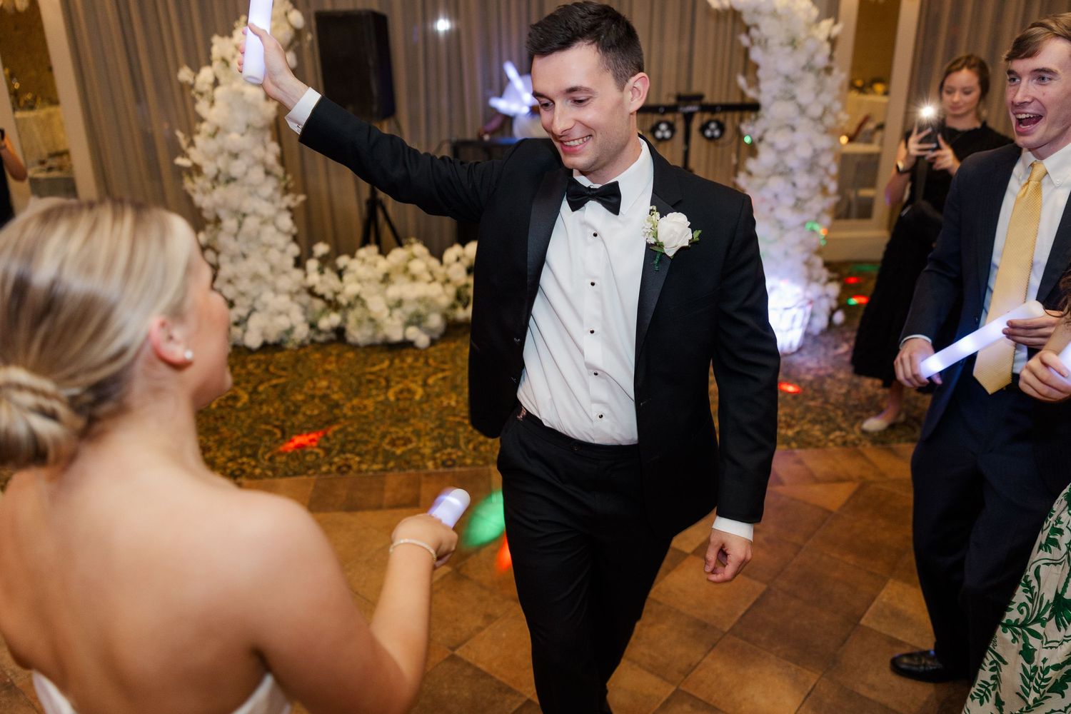 Wedding reception scene with festive decor and guests dancing in formal attire.