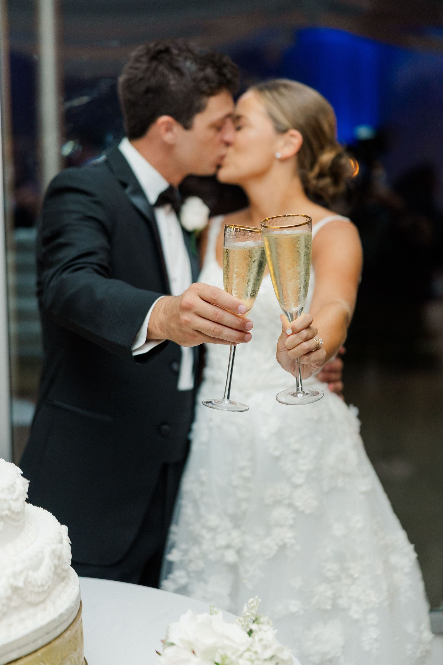 Champagne toast and wedding cake celebration with bride and groom in formal attire.