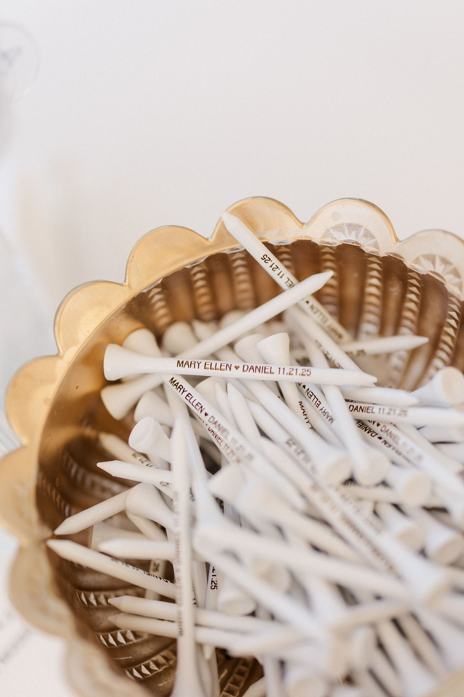 White paper straws arranged in a gold scalloped container for wedding reception drinks.