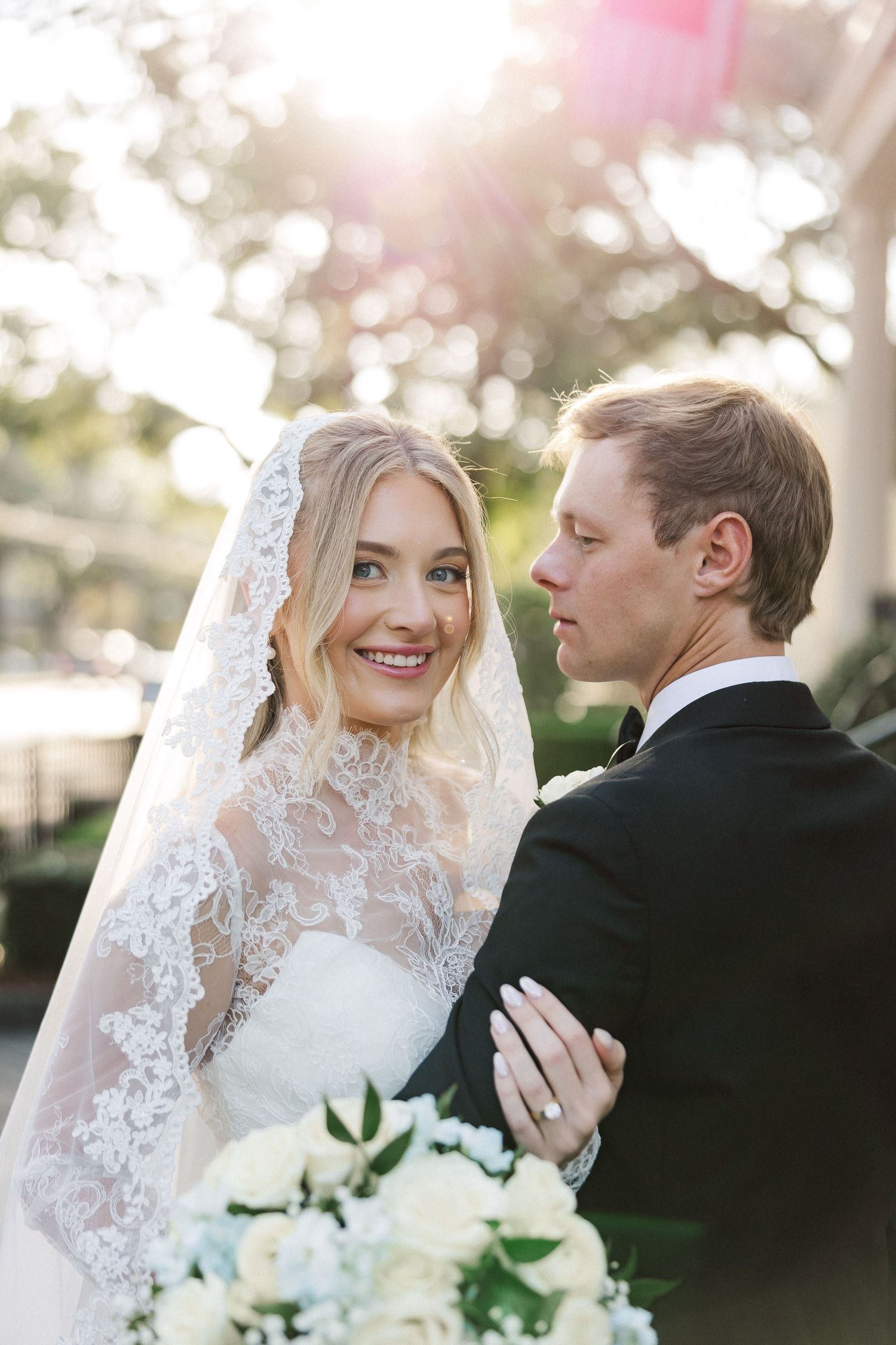 Romantic outdoor wedding portraits showing tender moments between newlyweds with white floral bouquet.