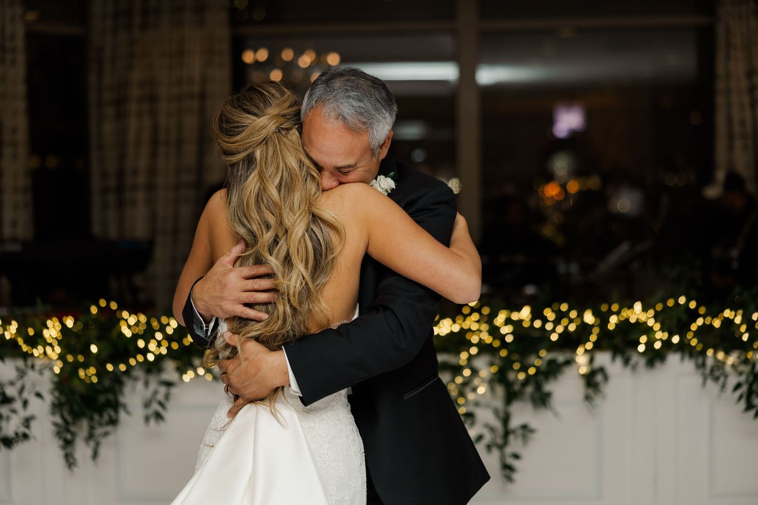 Wedding reception dance floor with romantic twinkle lights and greenery decorations.