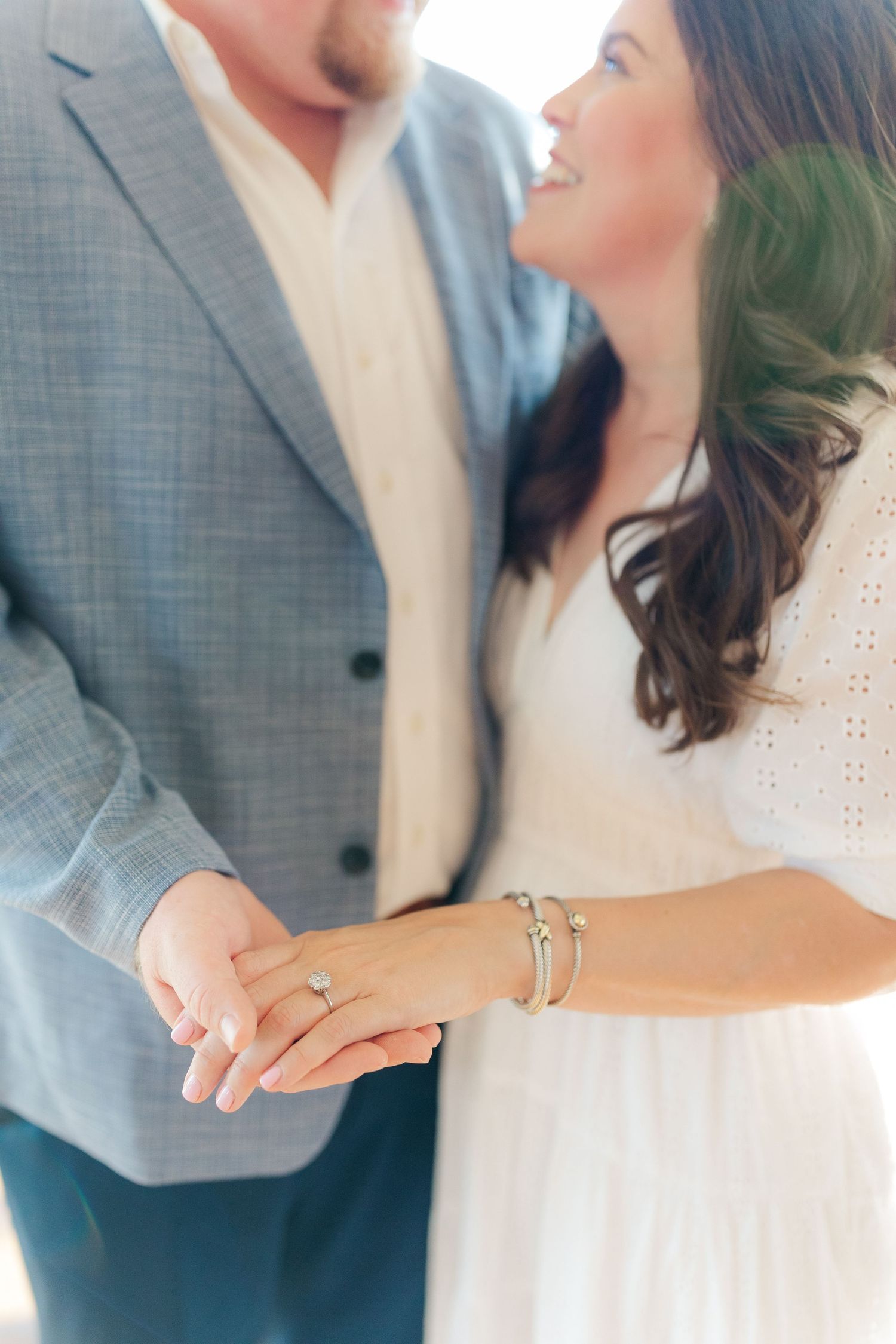 Close-up of couple's hands showing engagement ring and delicate bracelet details.