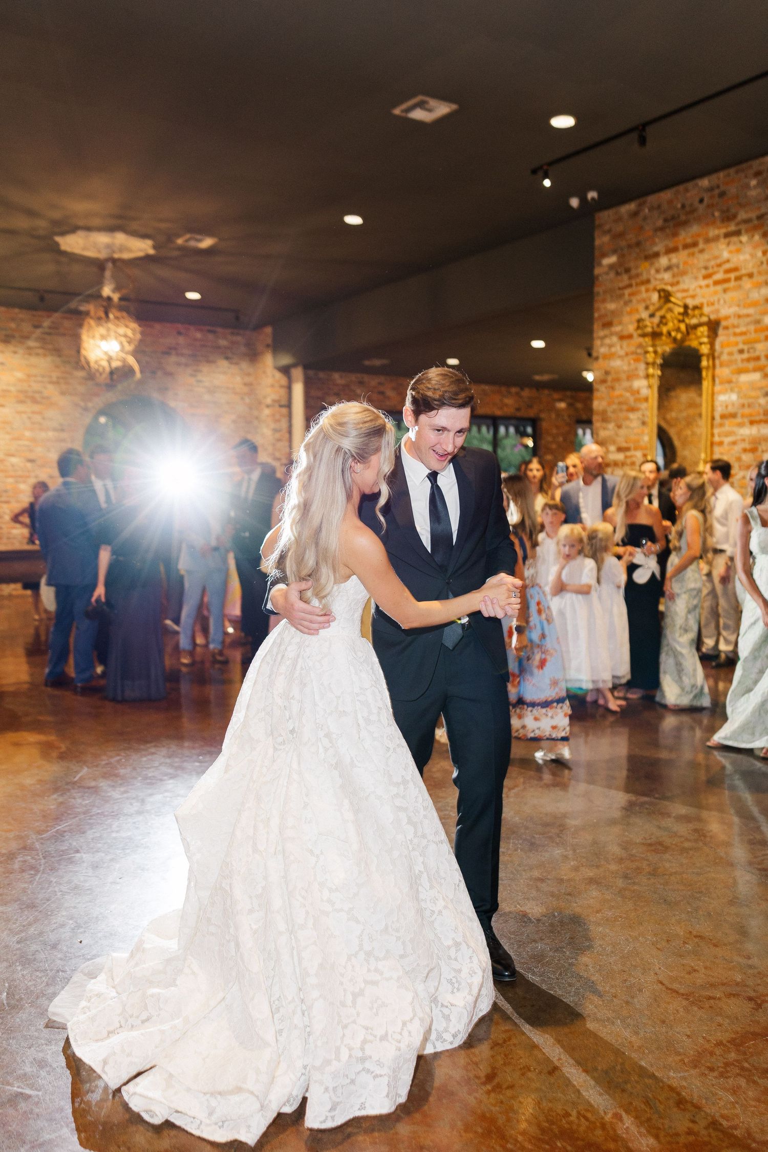 Bride and groom share their first dance in a rustic brick-walled wedding reception venue.