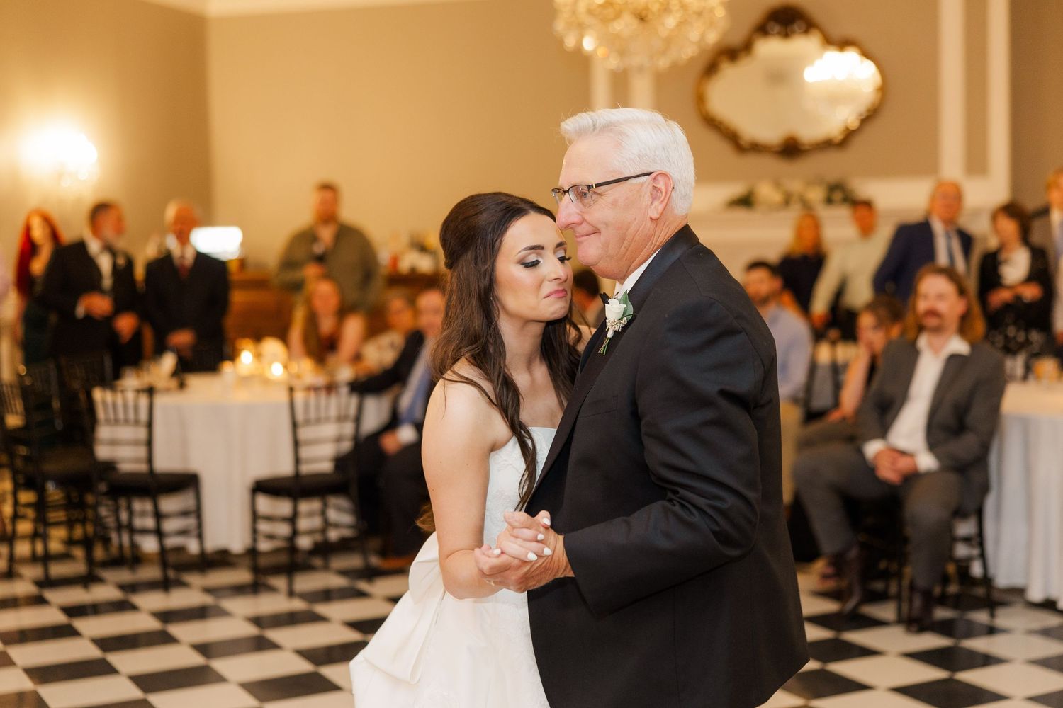 Wedding reception in an elegant ballroom with black and white checkered floor.