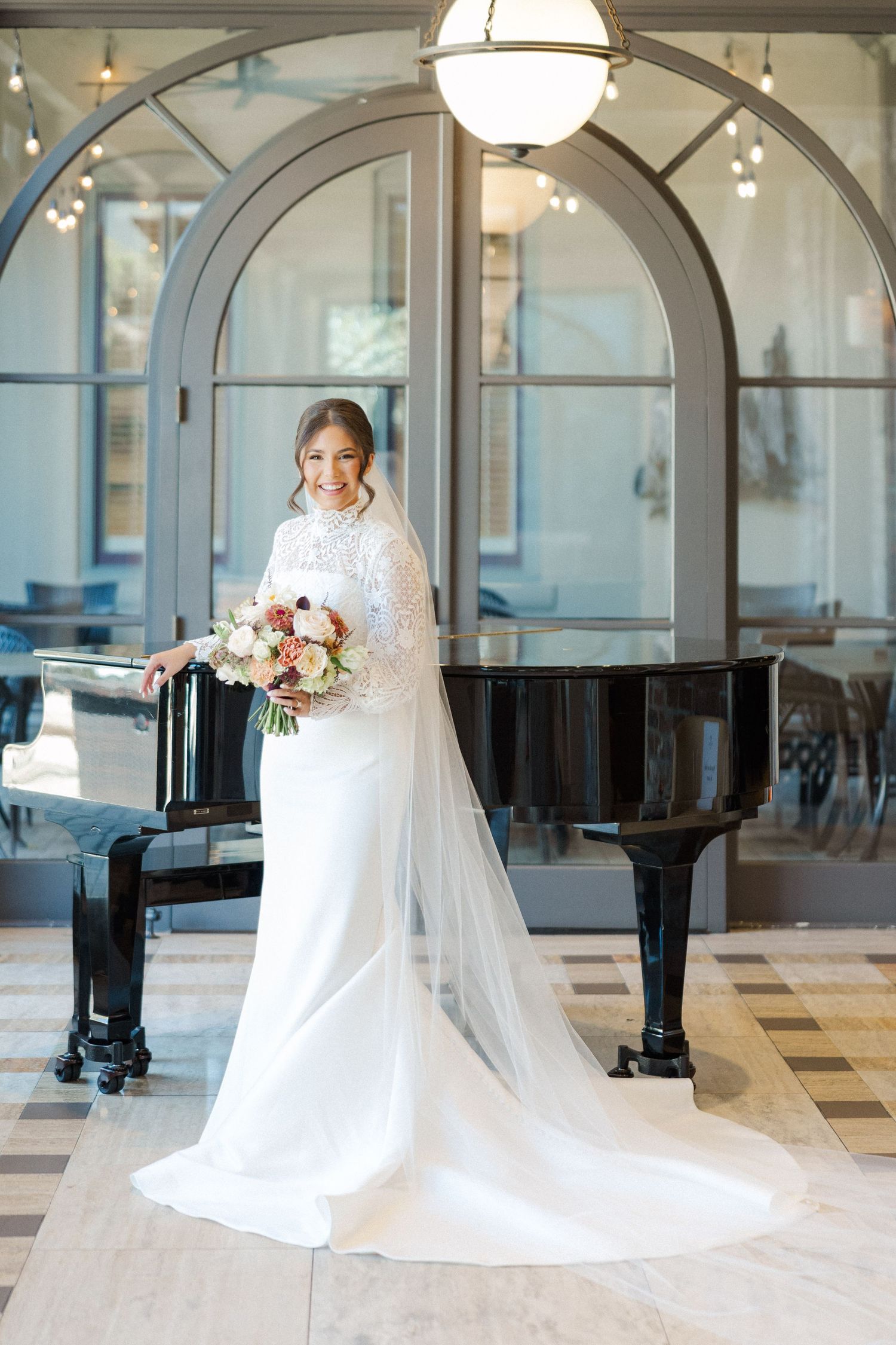 Classic bridal photos in an elegant venue with arched windows, featuring a flowing white gown and cathedral veil.