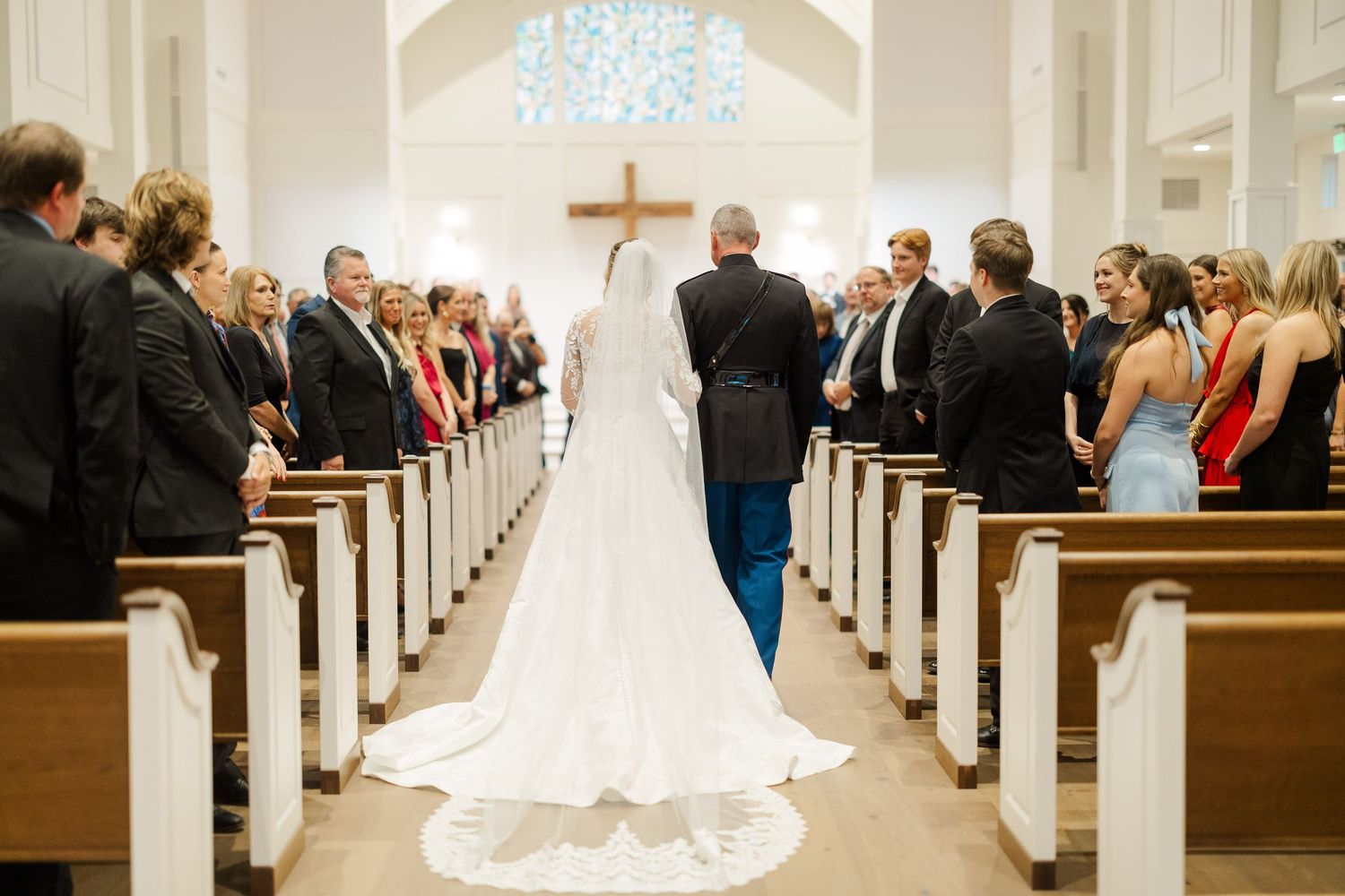 Wide view of church wedding ceremony with guests seated in wooden pews.