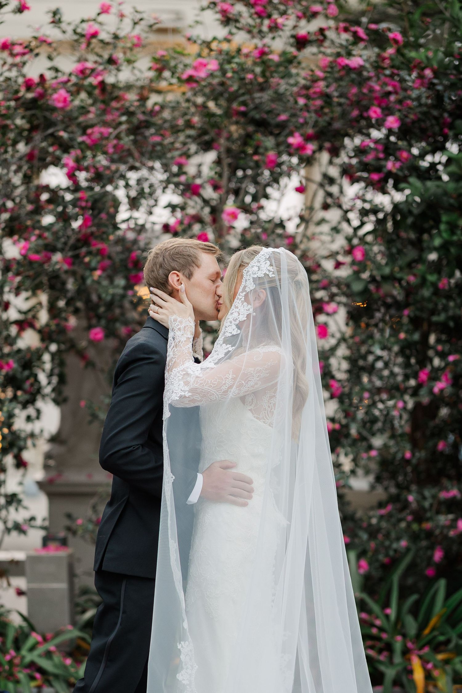 Romantic wedding portrait against blooming pink rose garden backdrop.