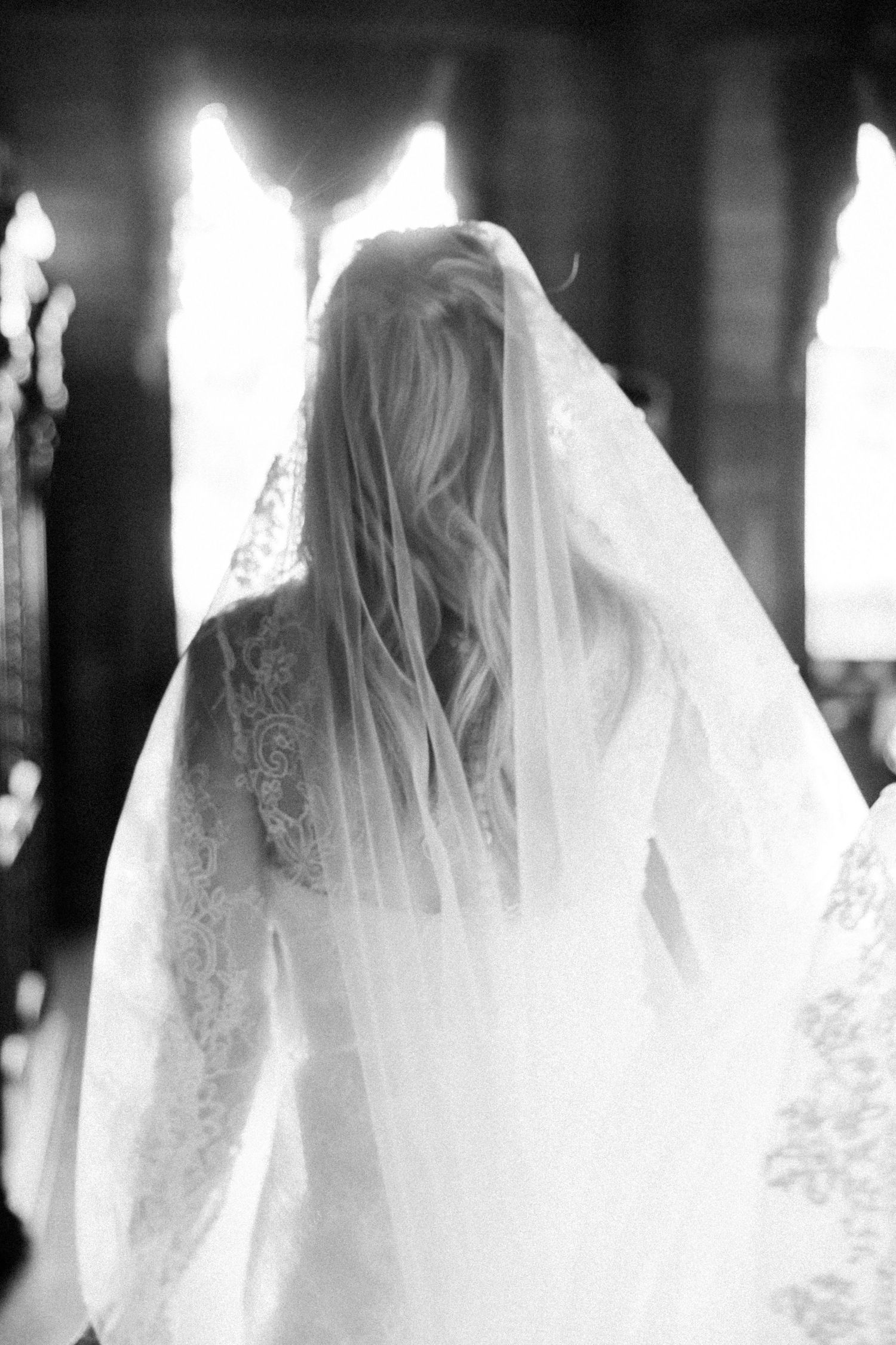 Ethereal black and white series showing flowing white wedding dress details and veil in natural light.