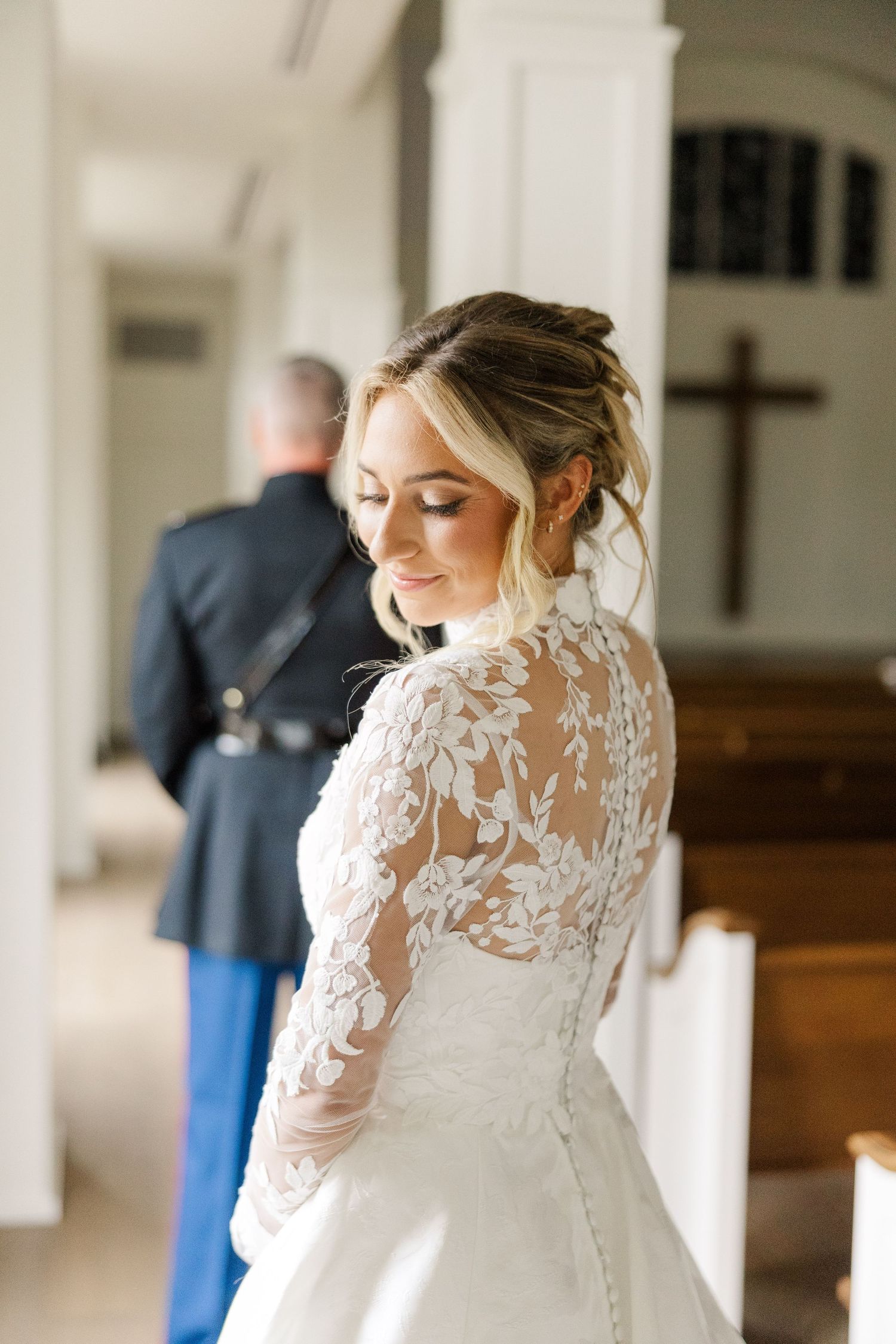 A wedding dress with intricate lace detailing and long sleeves is captured in an elegant indoor setting.