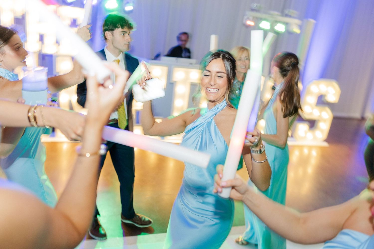 Wedding guests dancing and celebrating in turquoise and blue attire.