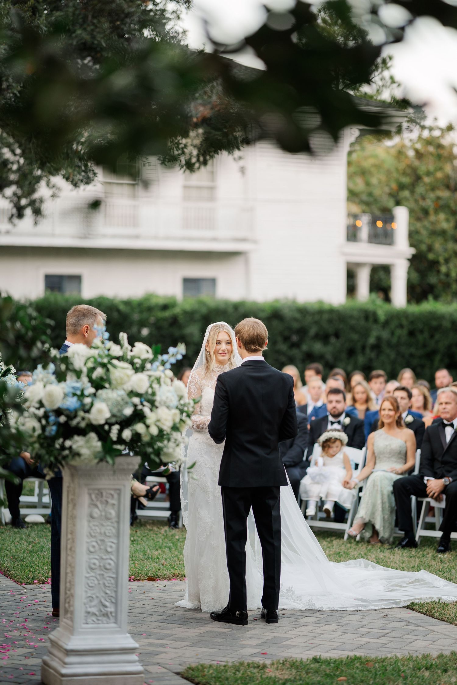 Outdoor wedding ceremony setup with decorative stone pedestals and white floral arrangements.