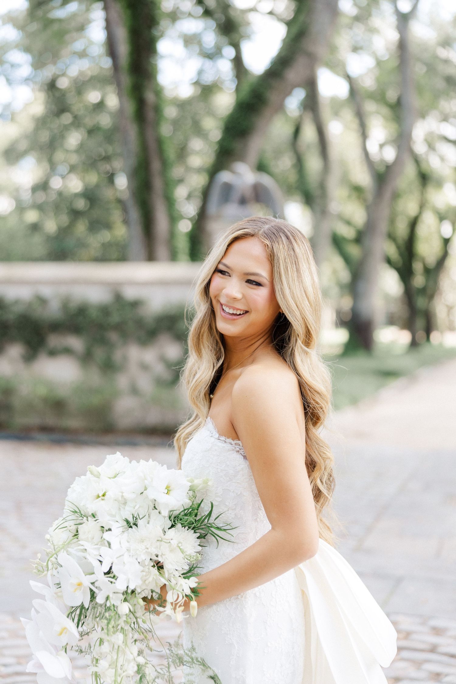 Beautiful bridal portrait outdoors featuring a white wedding bouquet with delicate flowers and greenery.