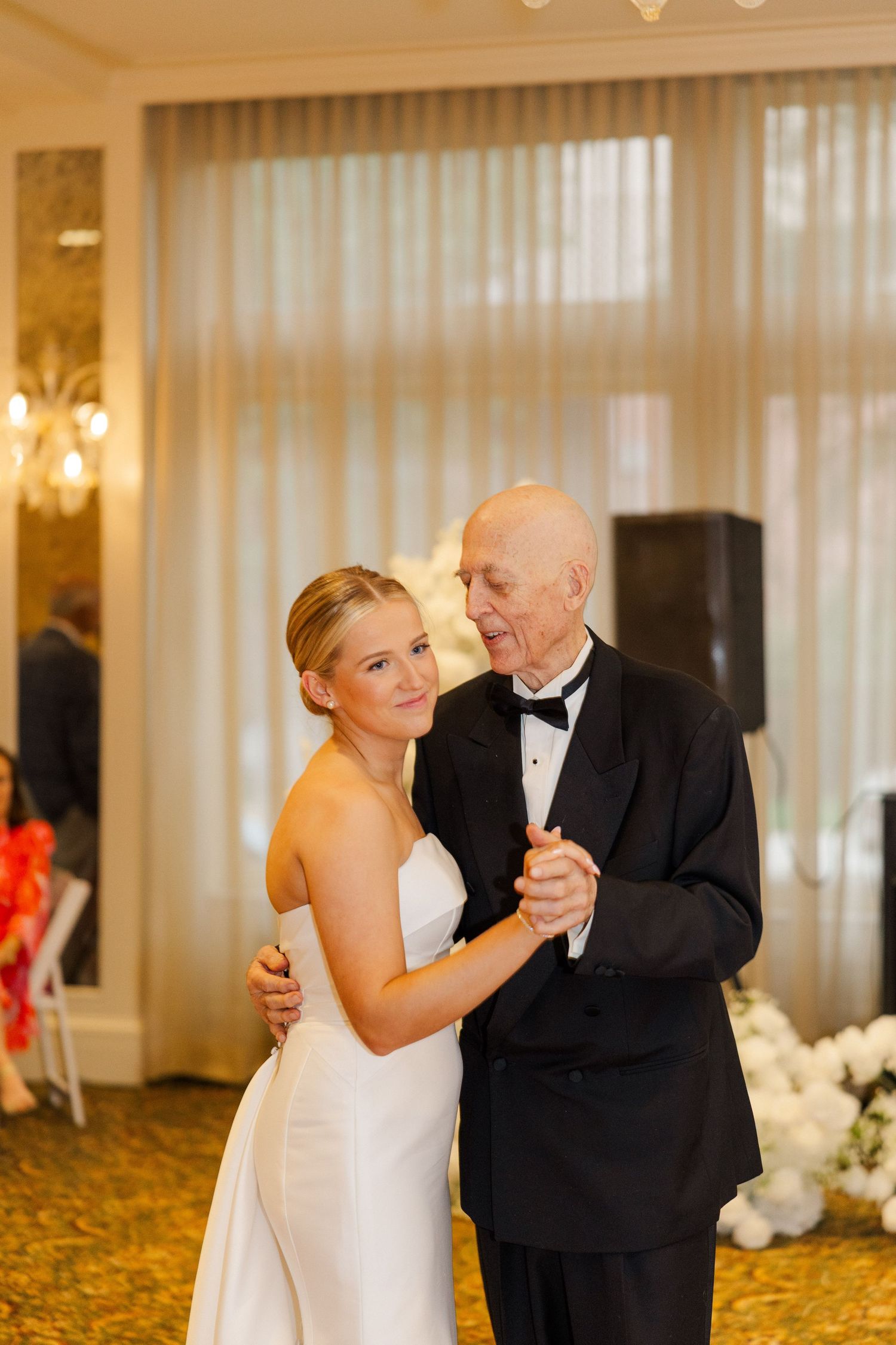 Elegant dance moment at a formal wedding reception in a grand ballroom with decorative lighting.
