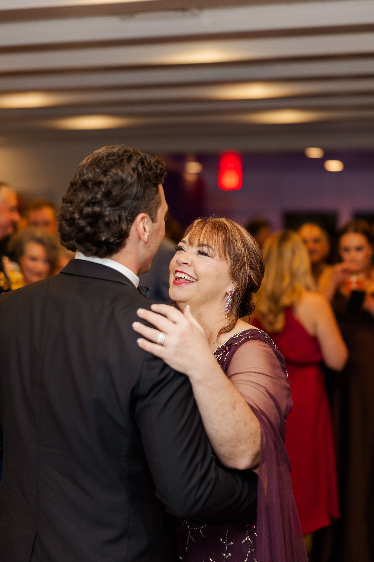 Wedding reception guests share a joyful dance moment under warm lighting.