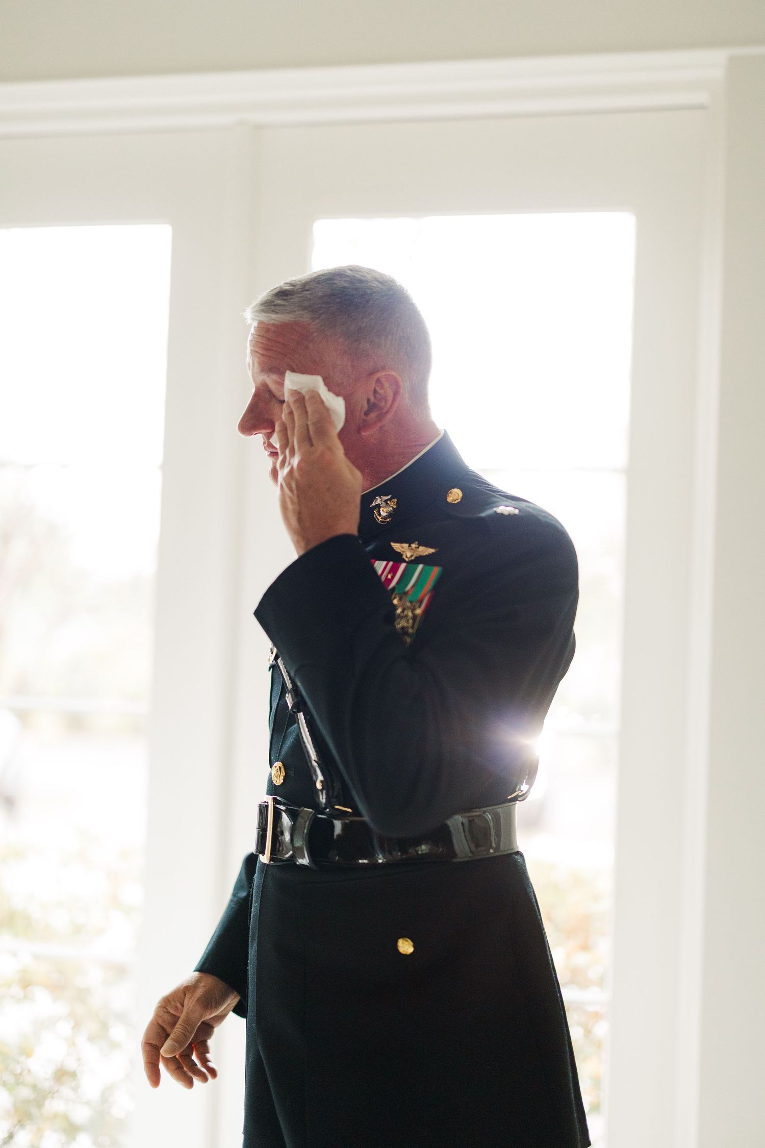 Military servicemen in dress uniforms stand in bright sunlit room.