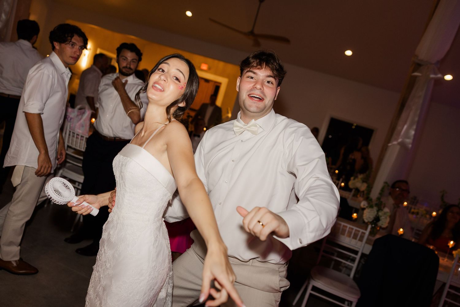 Bride and groom laugh and dance together joyfully on the dance floor at their wedding reception.