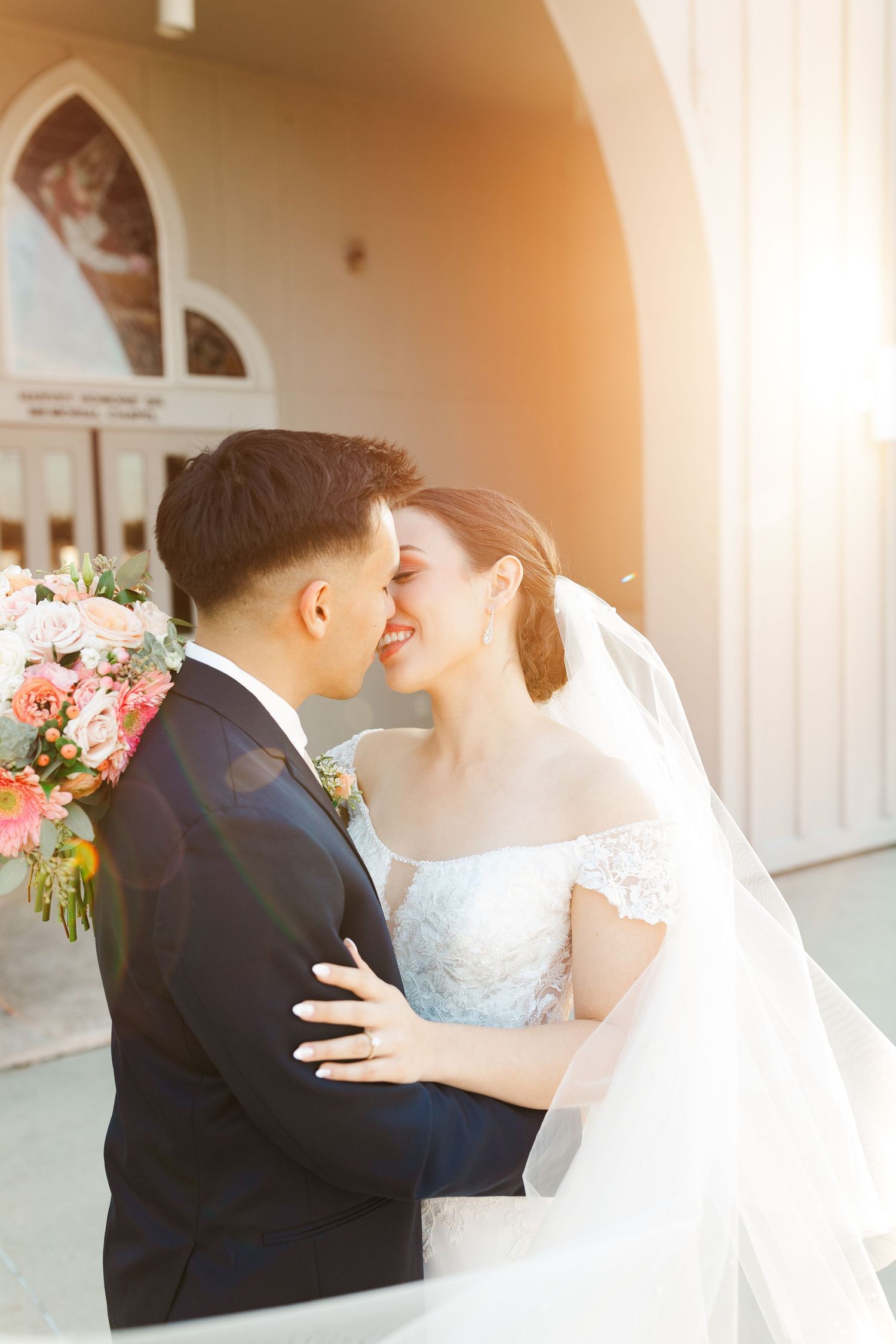 Wedding couple sharing romantic moment under arched church doorway.