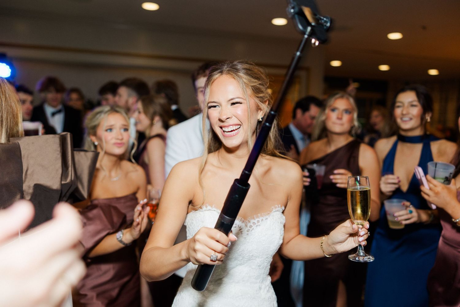 Bride celebrating with guests on dance floor at wedding reception.
