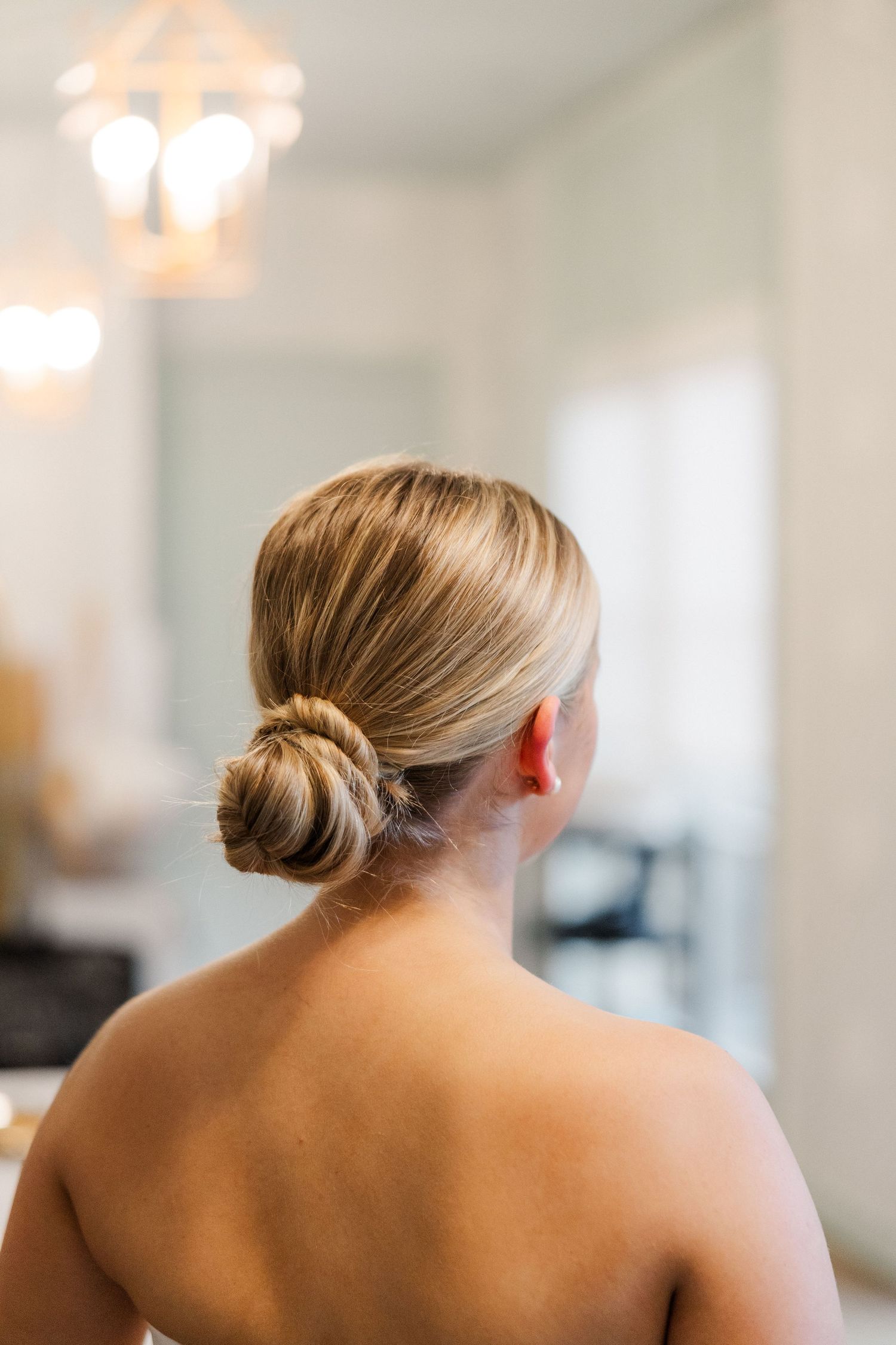 Elegant bridal hairstyle shown from behind in a classic low bun style.