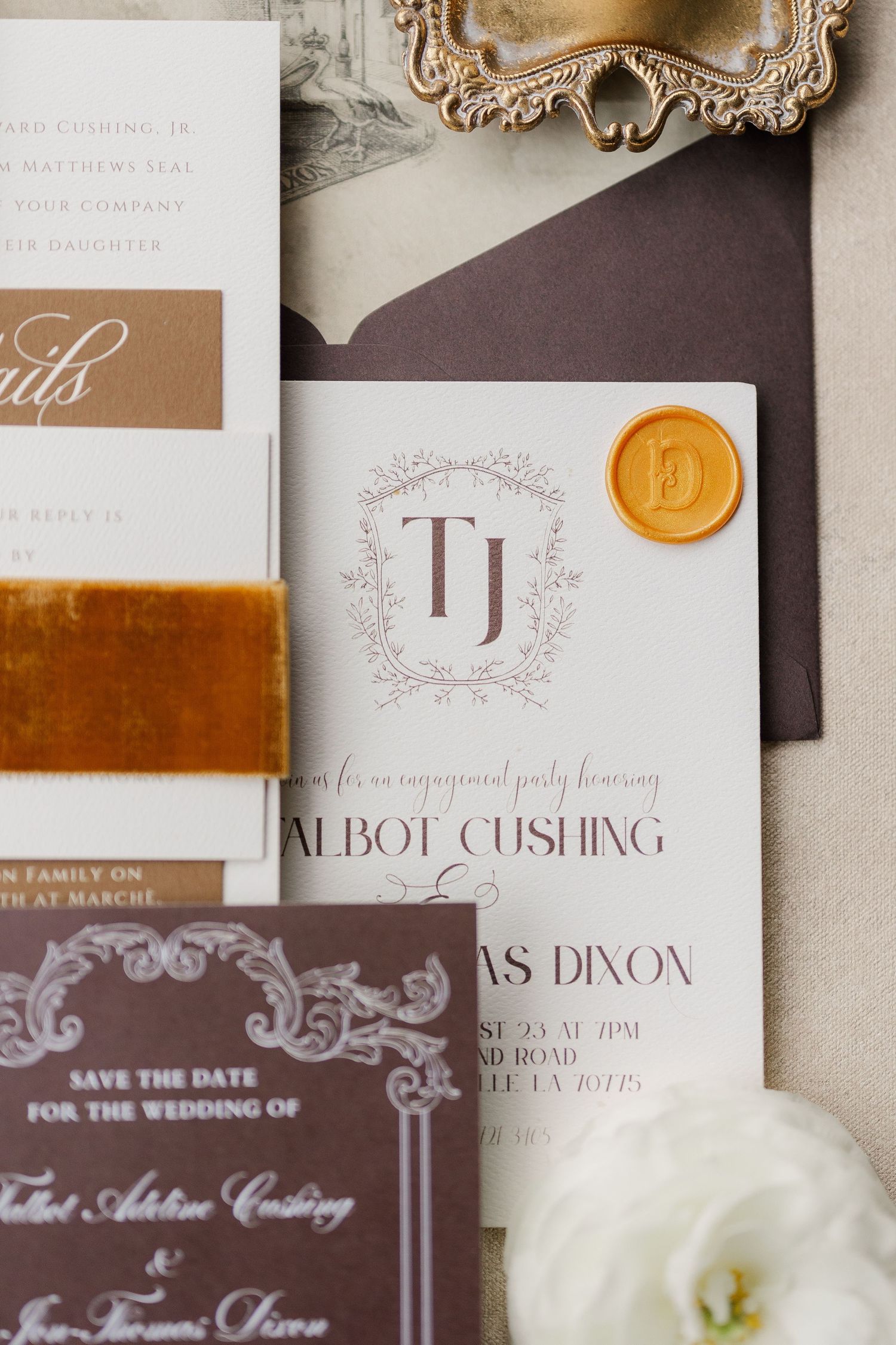 Elegant wedding invitation suite featuring velvet ribbons, gold wax seals, and ornate calligraphy in brown and white tones.