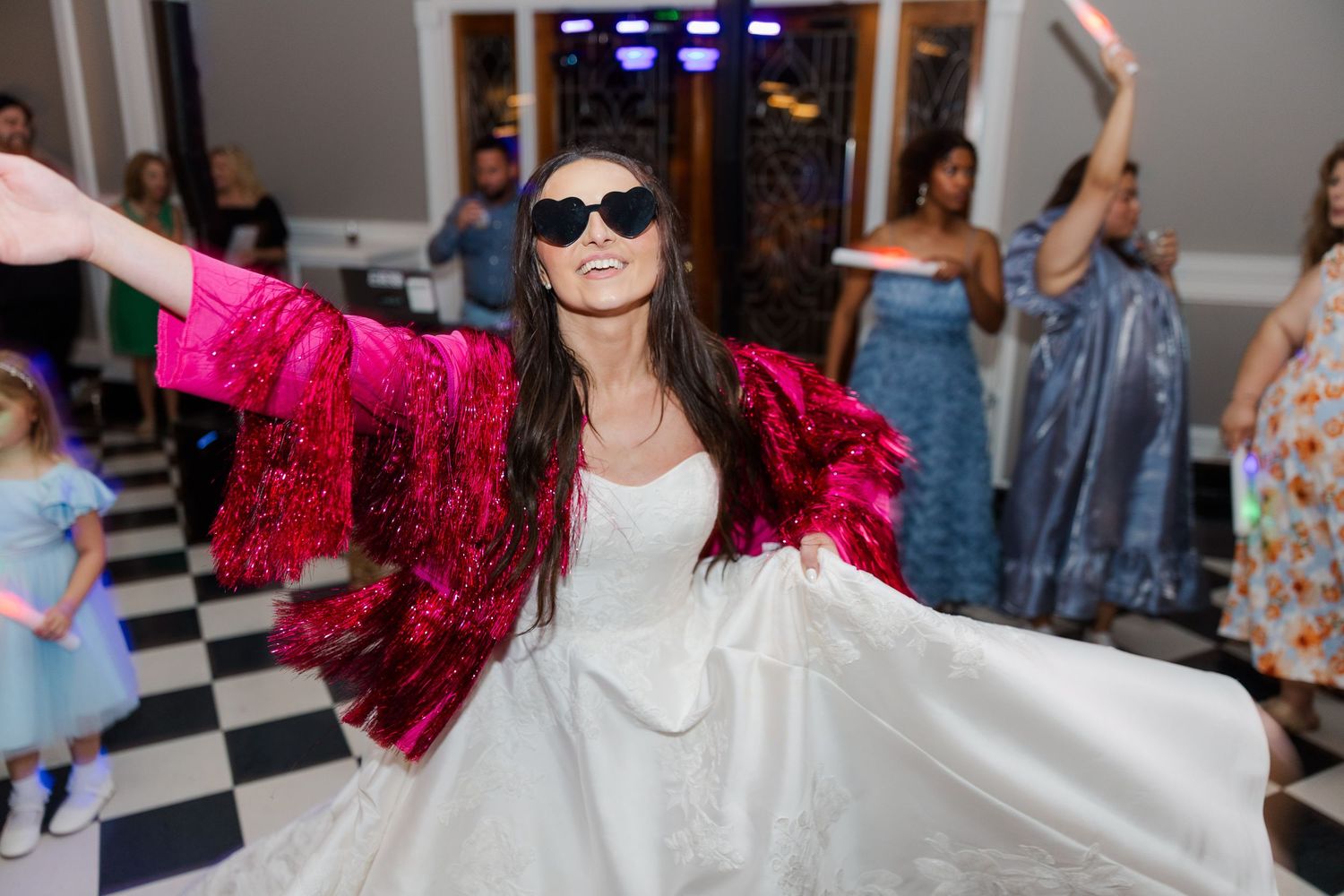 Wedding reception dance party with guests celebrating under colorful lights.