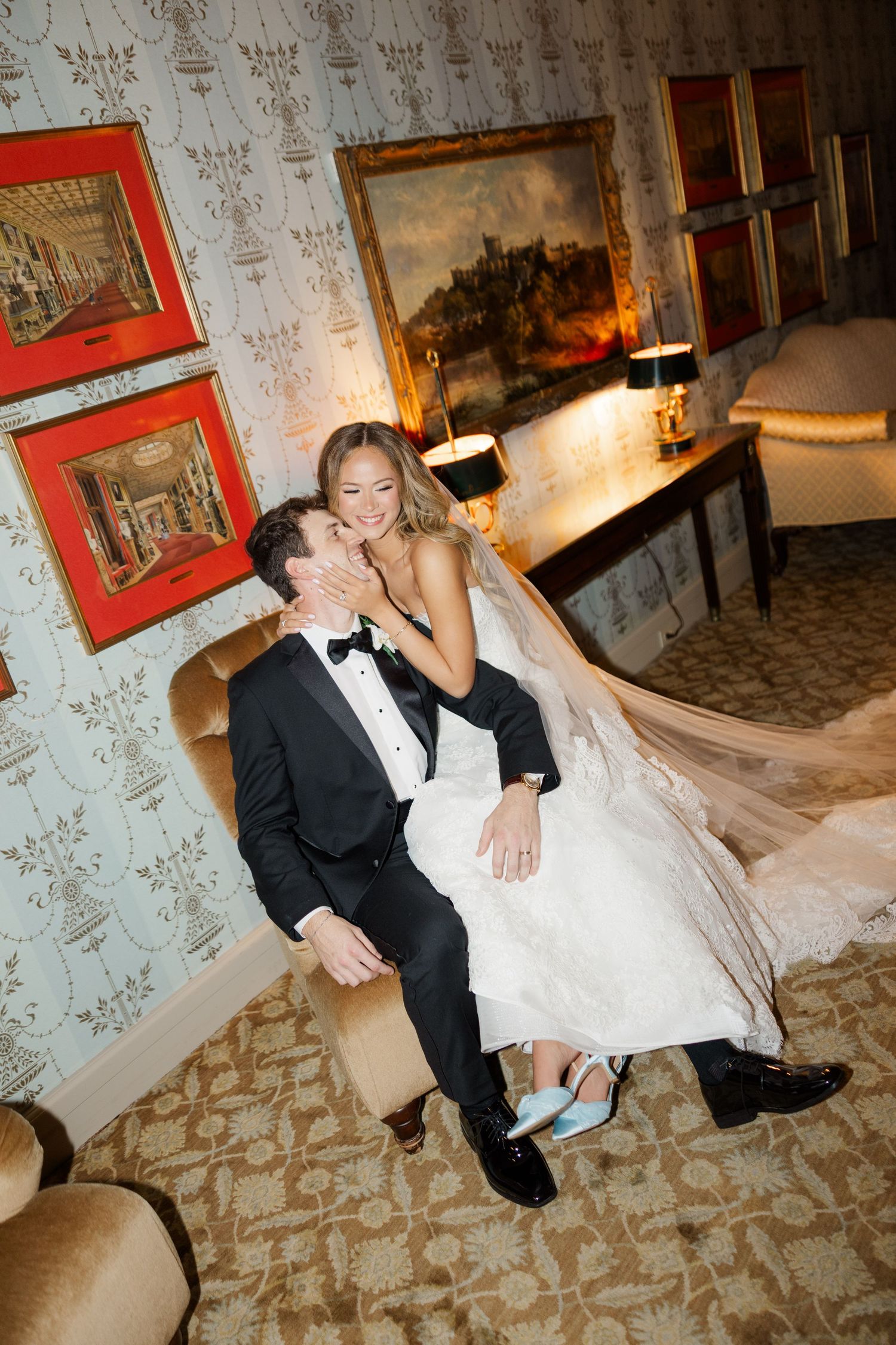 Playful wedding couple poses on vintage patterned wallpaper background.
