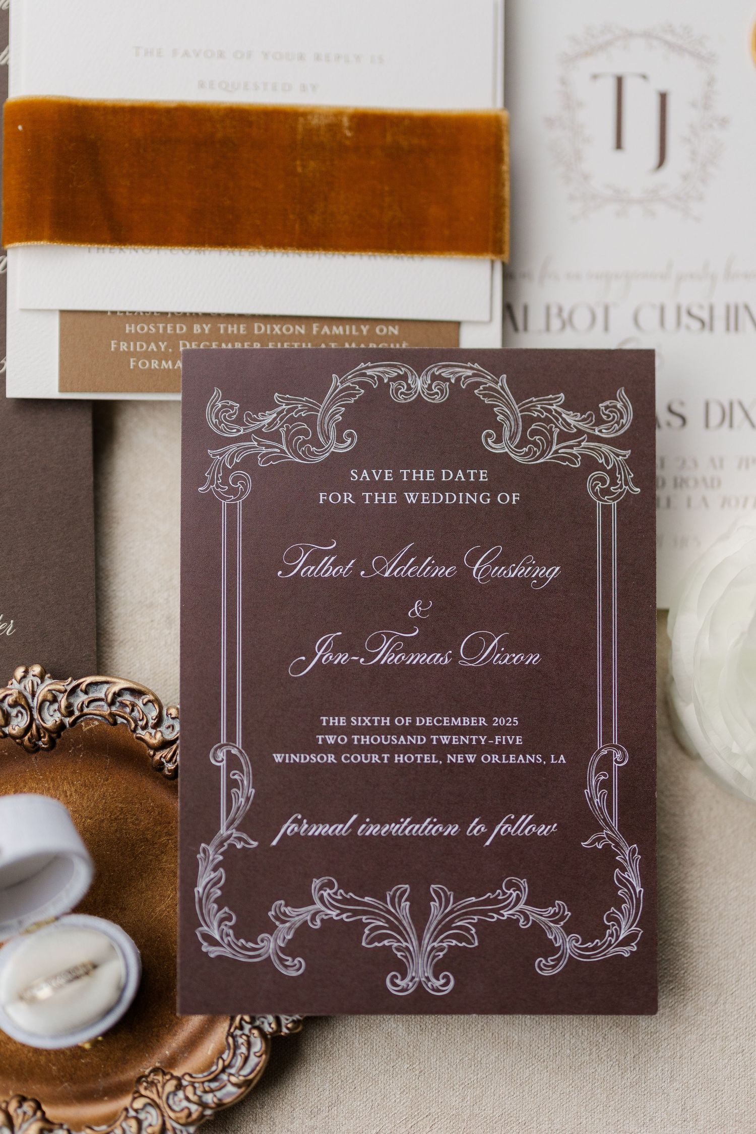 Elegant brown and white wedding save-the-date card with ornate scrollwork design and velvet ribbon accents.