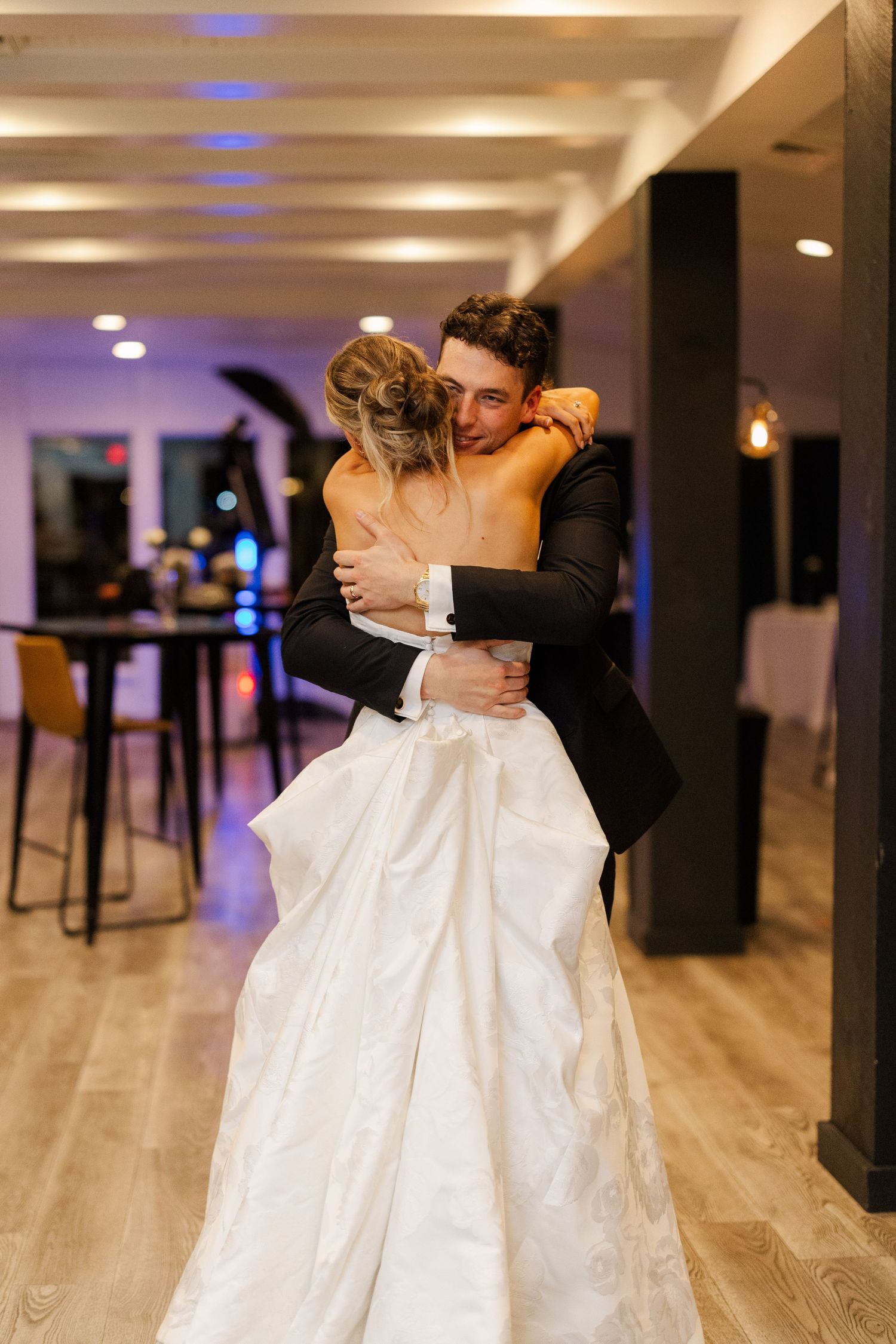 Romantic dance moment captured in a modern reception space with purple ambient lighting.