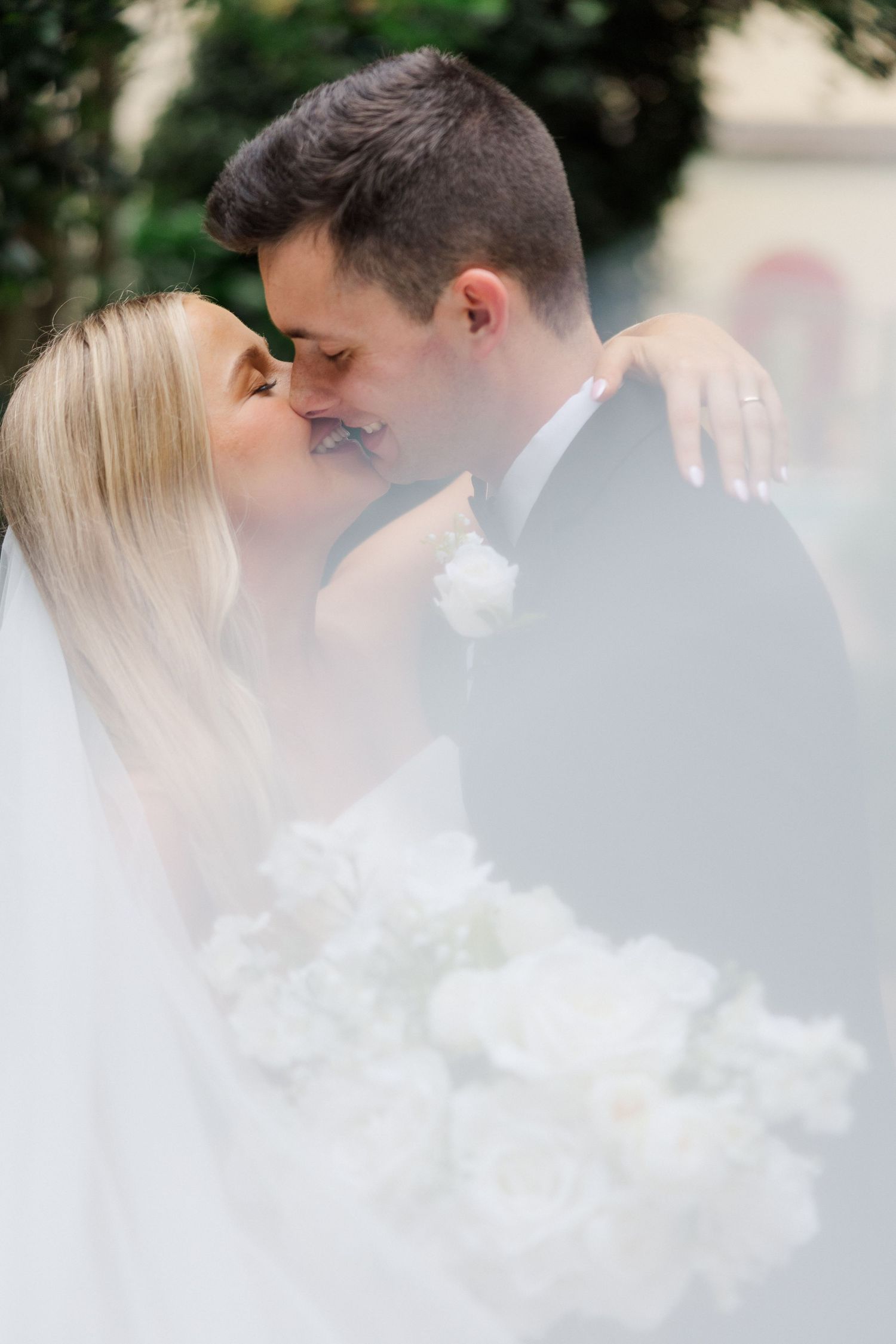 Artistic wedding portraits through delicate veil creating dreamy, romantic atmosphere.