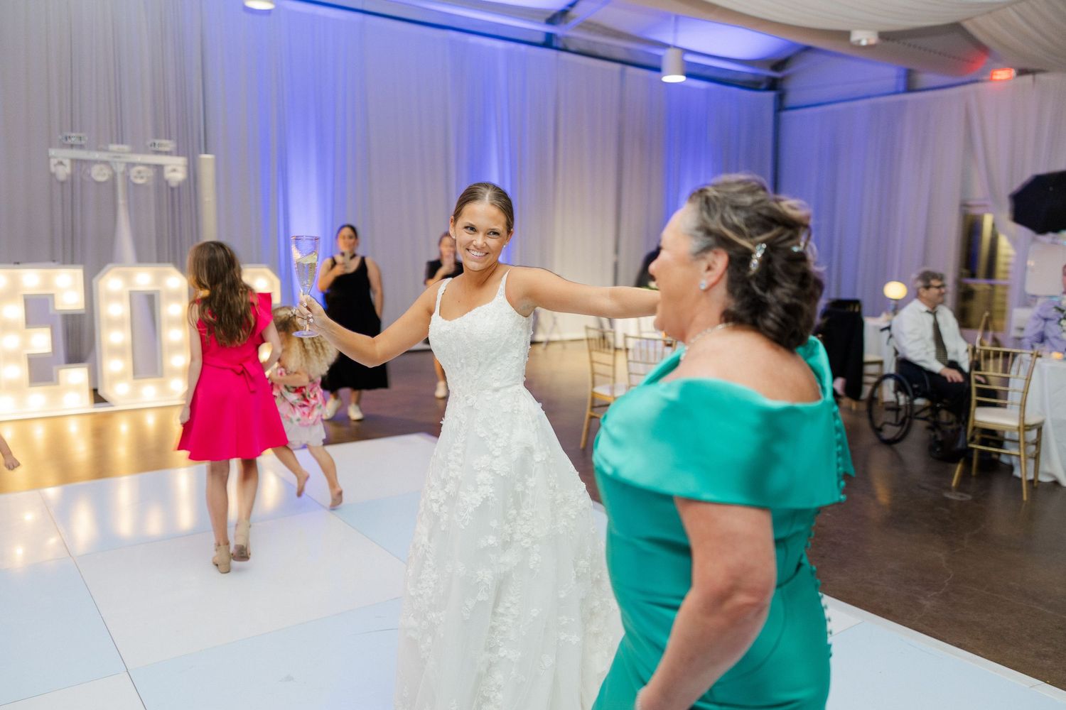 Wedding guests dancing and celebrating at a reception with blue mood lighting.