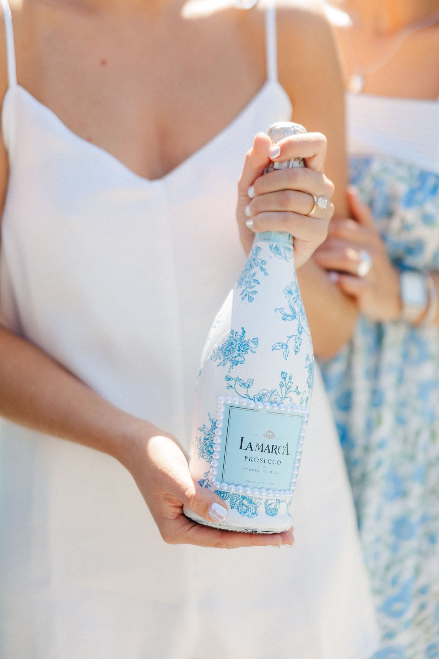 Decorative white and blue floral patterned bottle being held against light background.