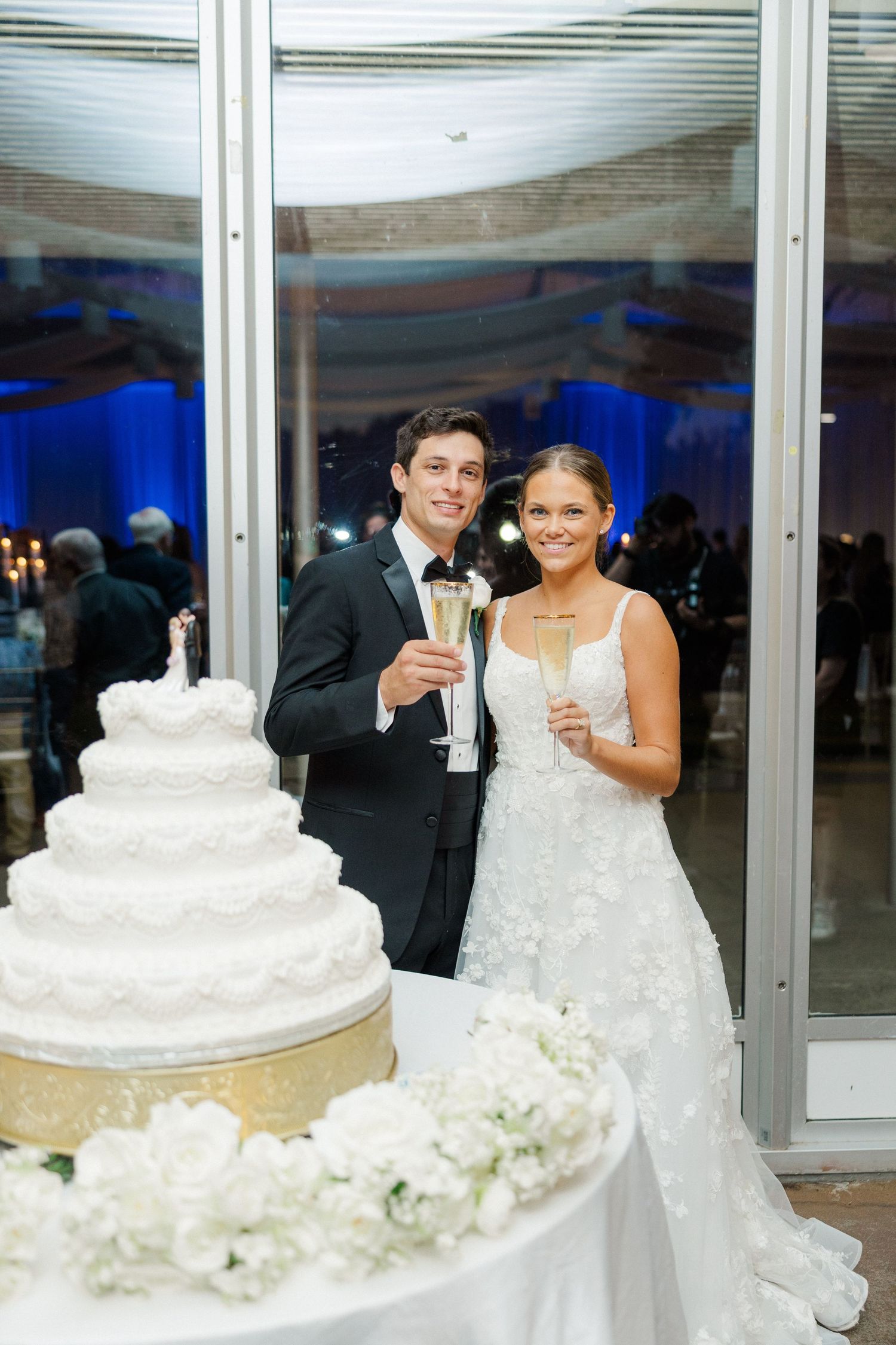 An elegant wedding reception scene with a multi-tiered white cake and champagne toast.