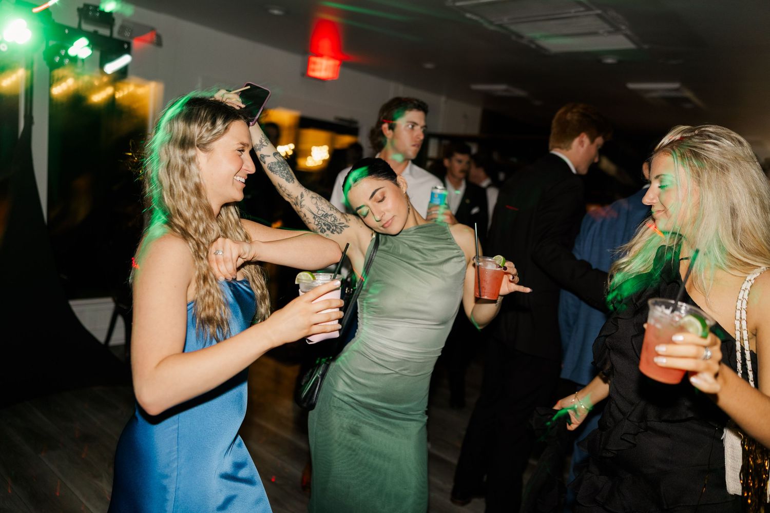Wedding reception guests dancing and celebrating under colorful party lights.