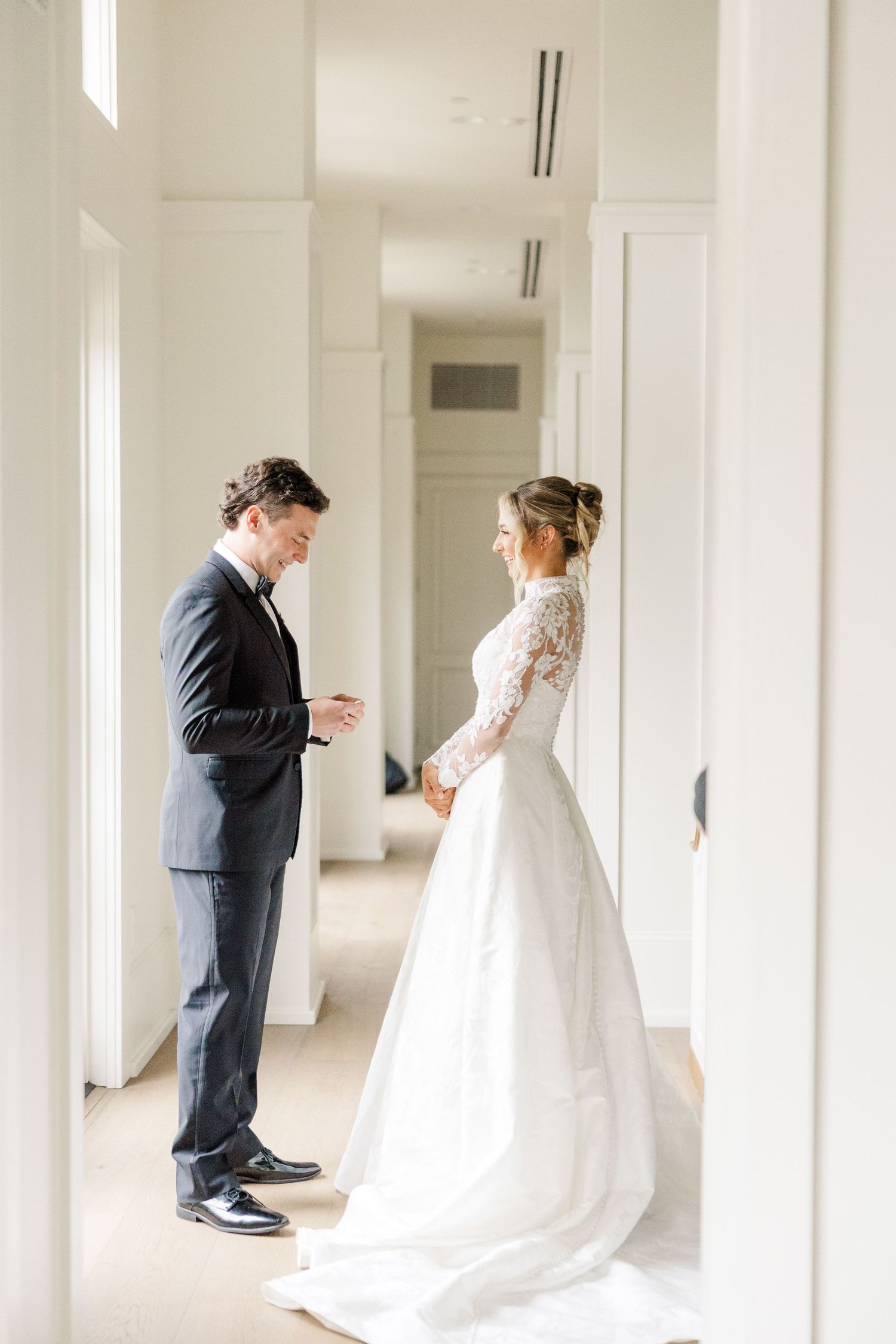 A first look wedding moment captured in a bright hallway as the couple sees each other before the ceremony.