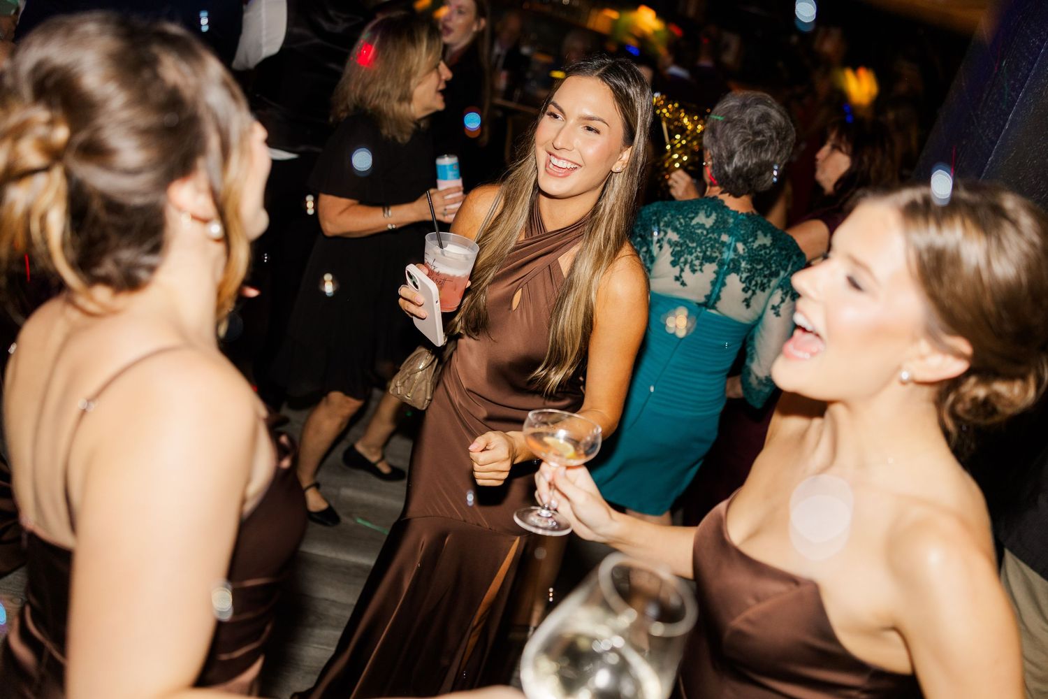 Wedding guests dancing and celebrating at evening reception with festive atmosphere.