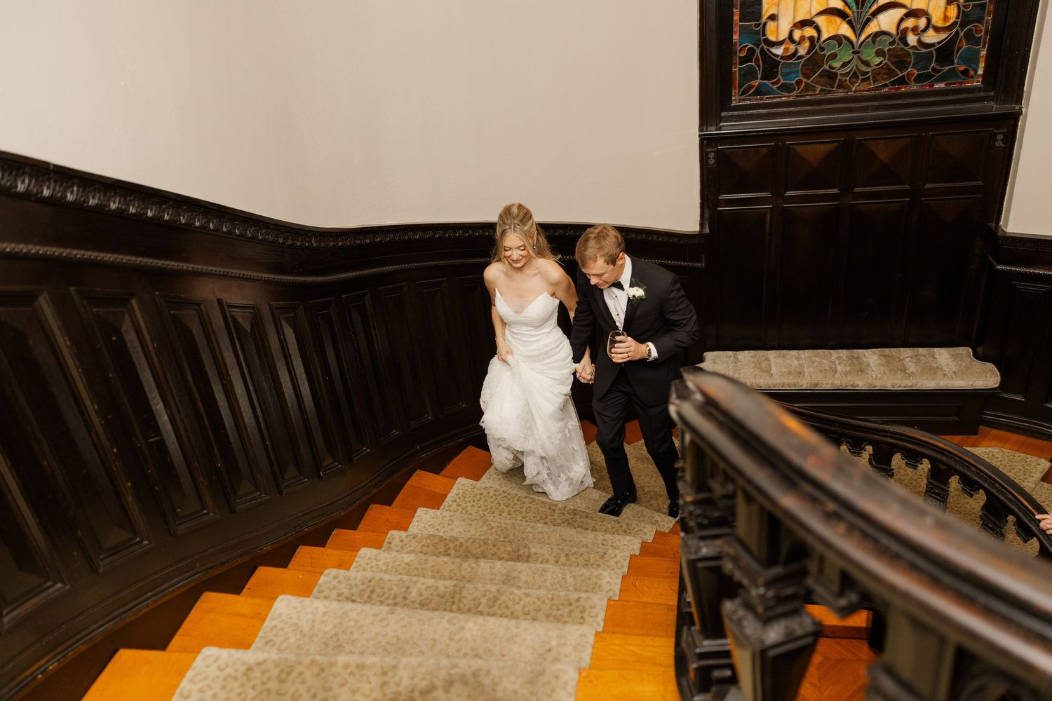 A couple descends an elegant staircase during their wedding celebration.