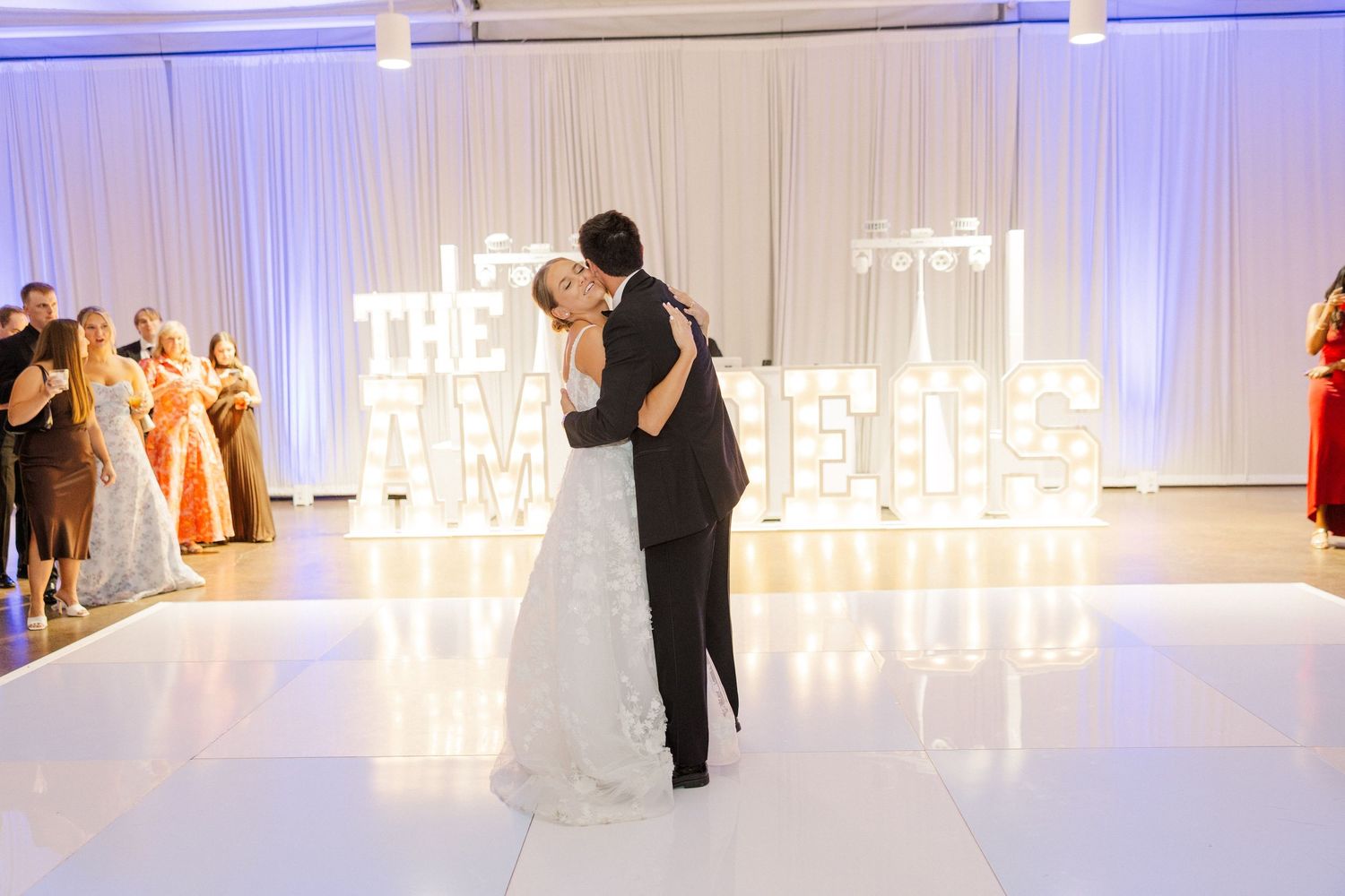 Wedding reception dance floor with blue uplighting and illuminated marquee letters.