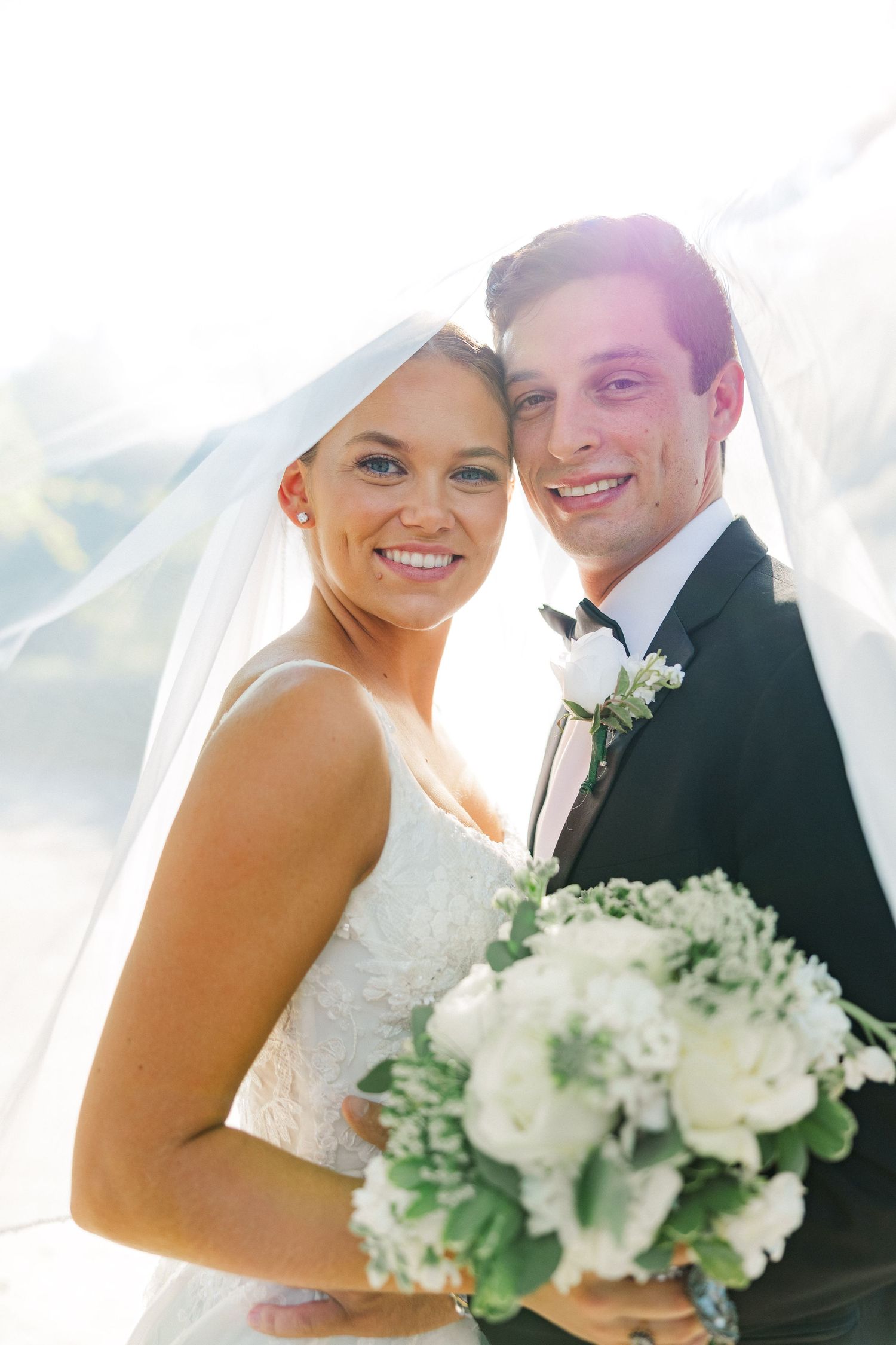 Sun-drenched wedding portraits showing joyful moments between couple with white bouquet.
