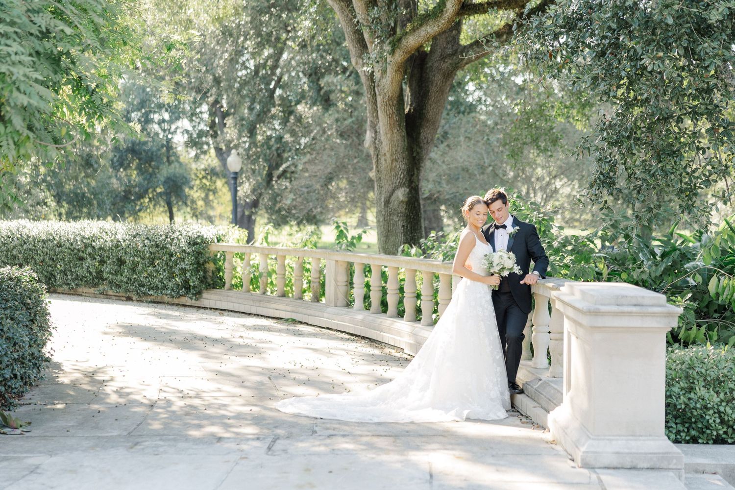 Romantic garden wedding photos taken on stone steps surrounded by lush greenery.