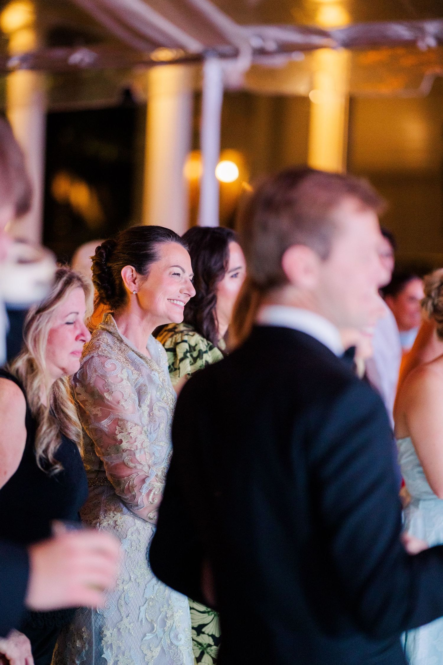 Wedding reception guests enjoying the celebration under warm ambient lighting.
