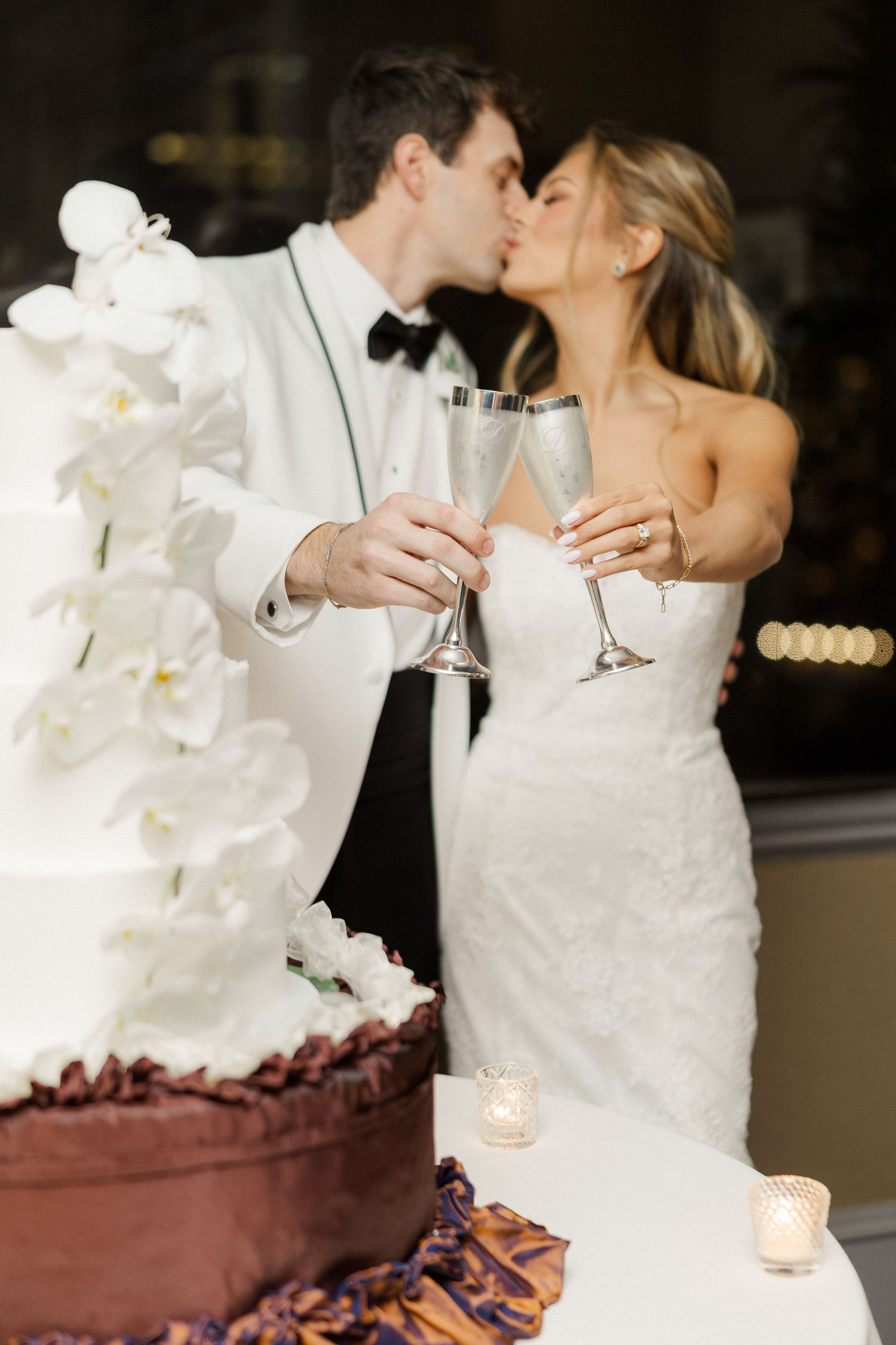 Wedding couple sharing intimate moment near elegant white orchid and cake display.