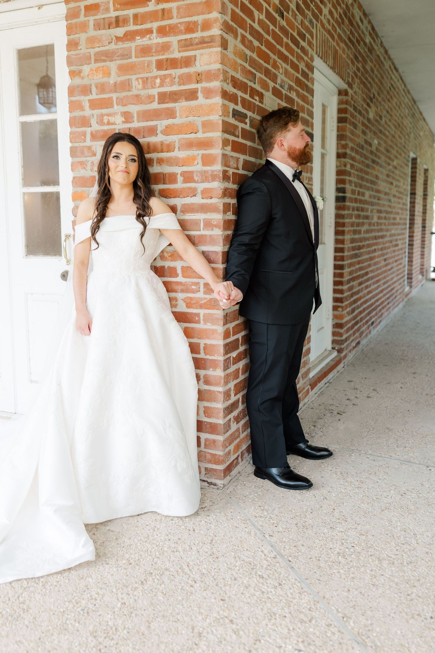 Bride and groom share a first look moment in a brick-lined corridor.