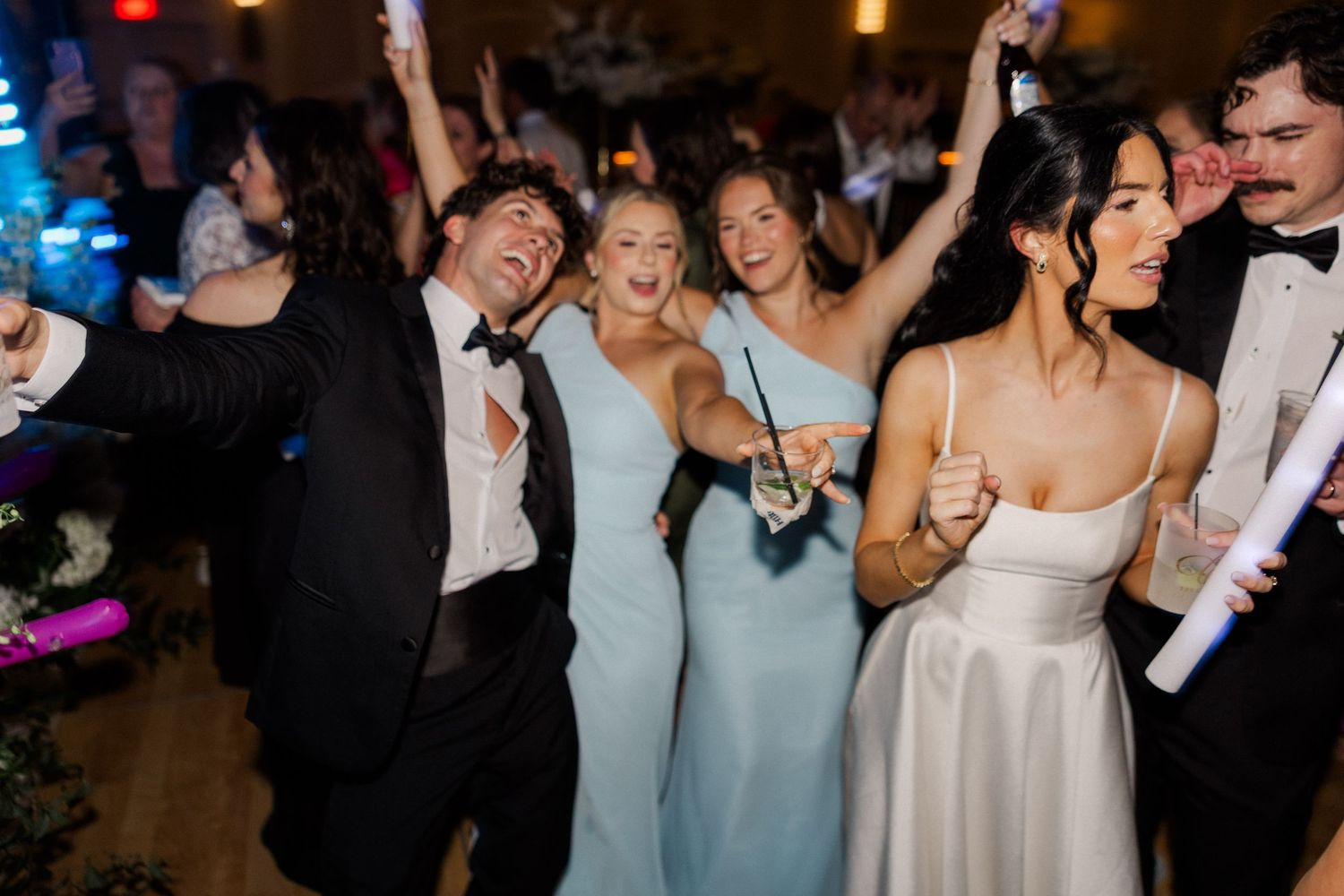 Bride and wedding guests celebrate joyfully on the dance floor at a lively wedding reception.