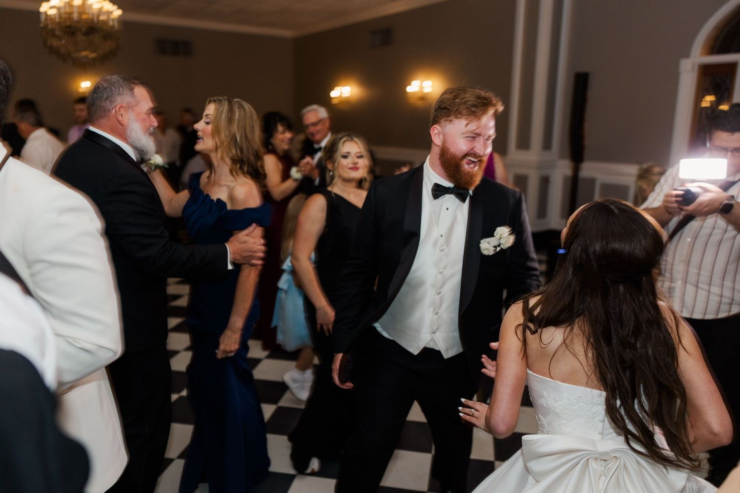 Wedding reception dance party with guests enjoying celebration in elegant ballroom.