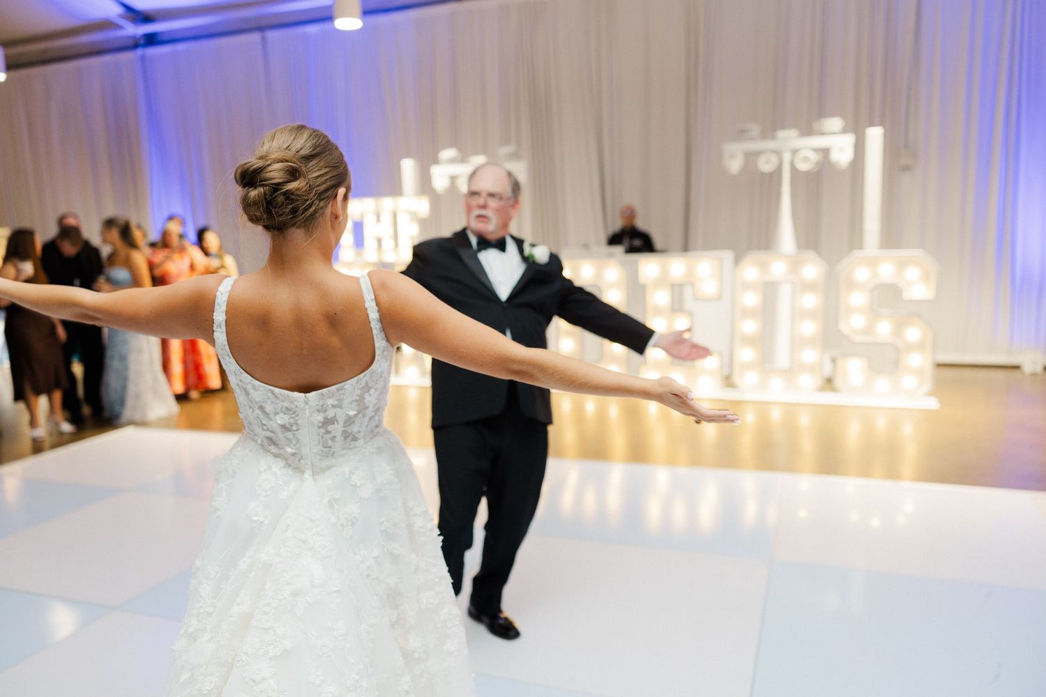 Wedding couple performing choreographed dance routine at reception with dramatic lighting.